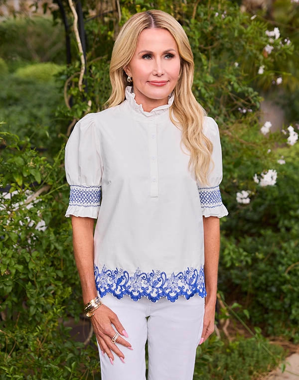 Woman wearing a white blouse with blue accents in a garden setting