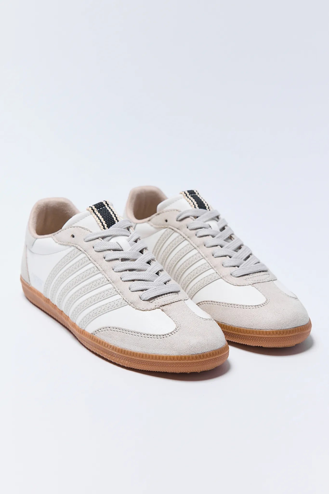 Pair of white Stevie Sneakers with brown soles on a light gray background