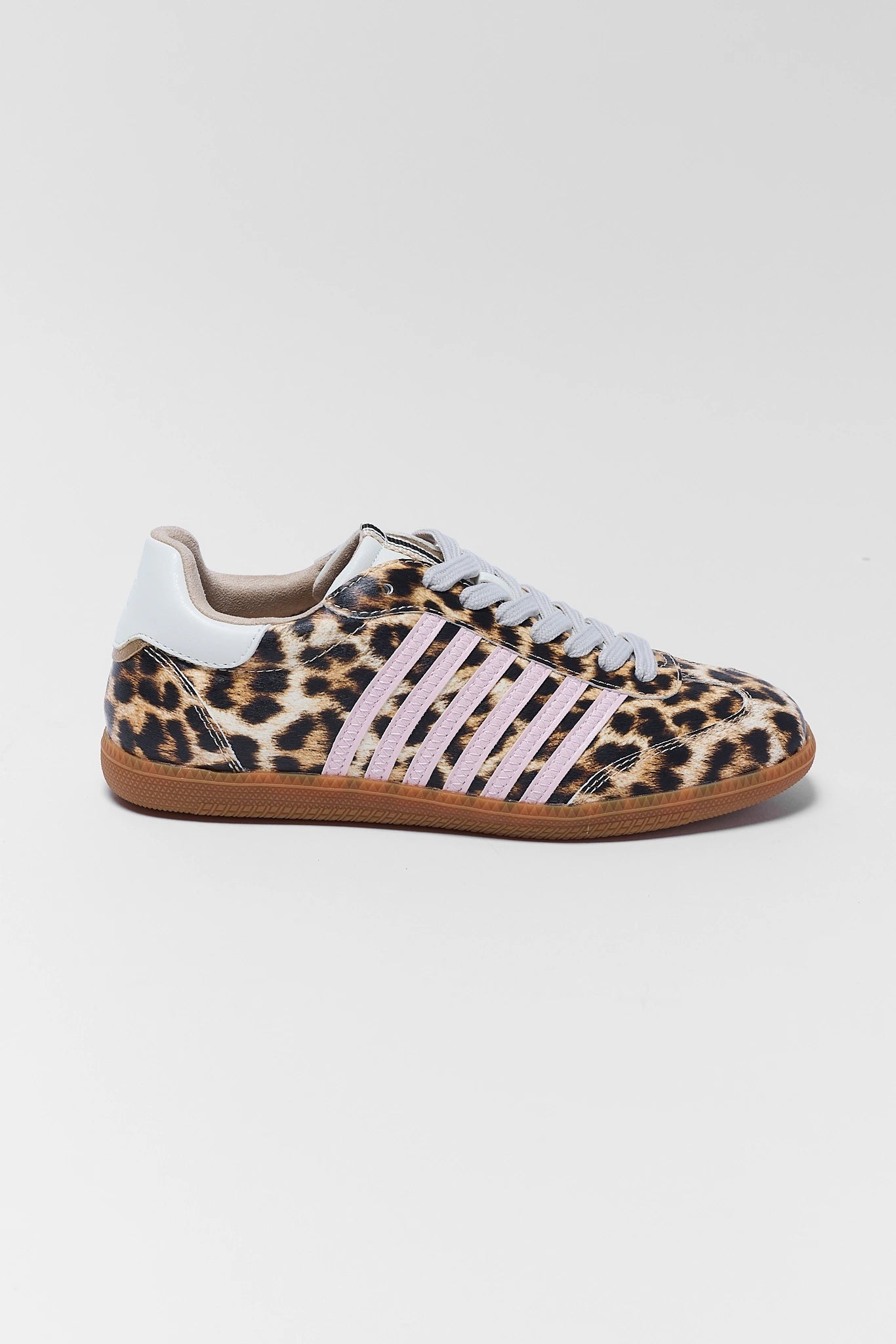 A low-top sneaker featuring a leopard print pattern on the upper, light pink three stripes, a white heel tab, and a brown gum sole, shown against a light gray background.