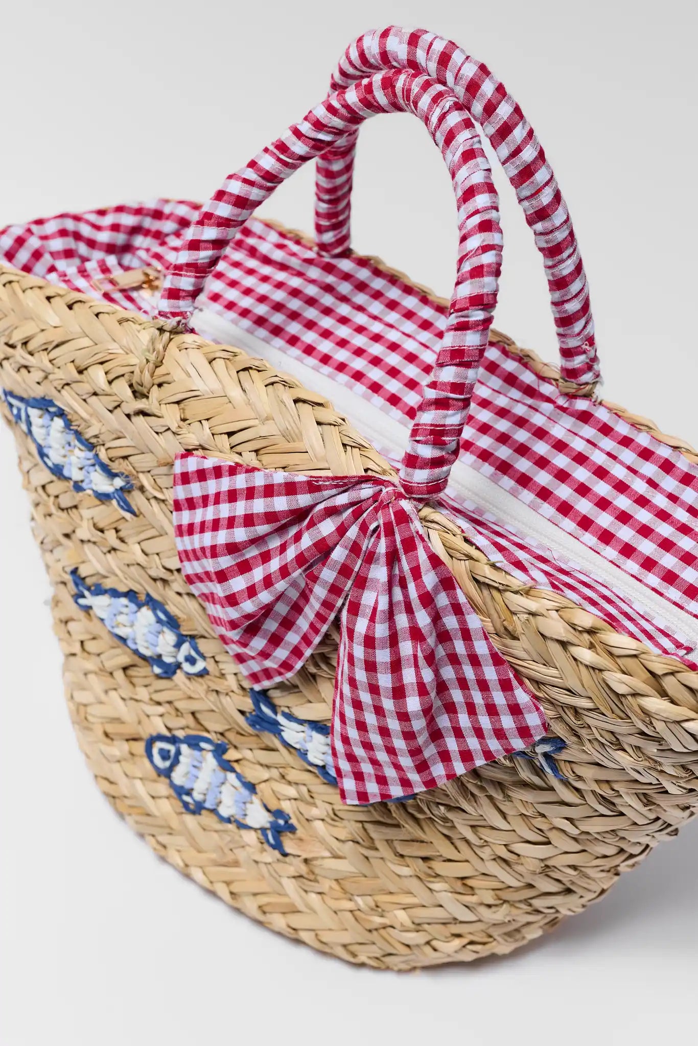 close up Woven basket with red and white checkered cover and blue fish pattern