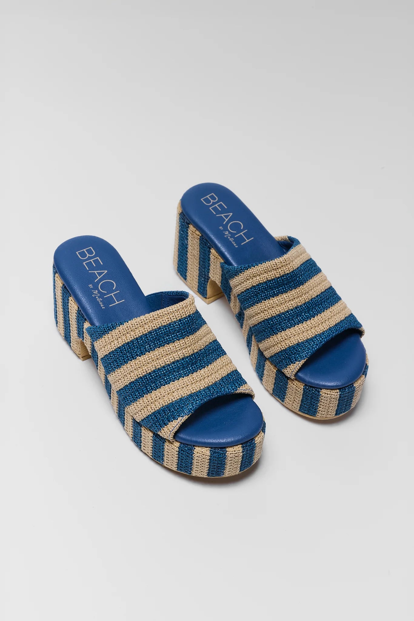 two Blue and beige striped sandals with branding on a white background