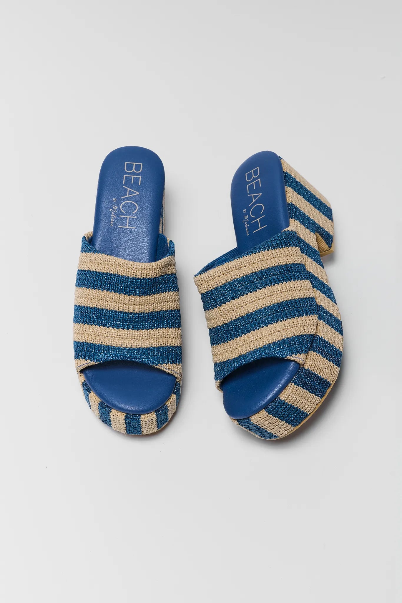 Pair of blue and beige striped slippers on a light gray background