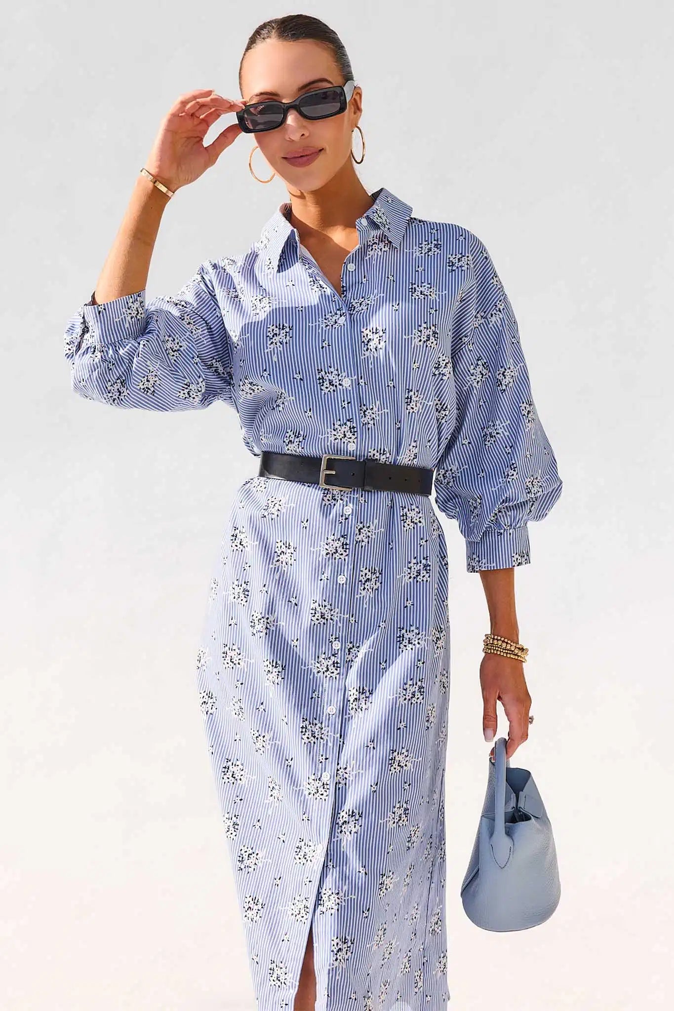 Woman wearing a blue floral dress with a white background