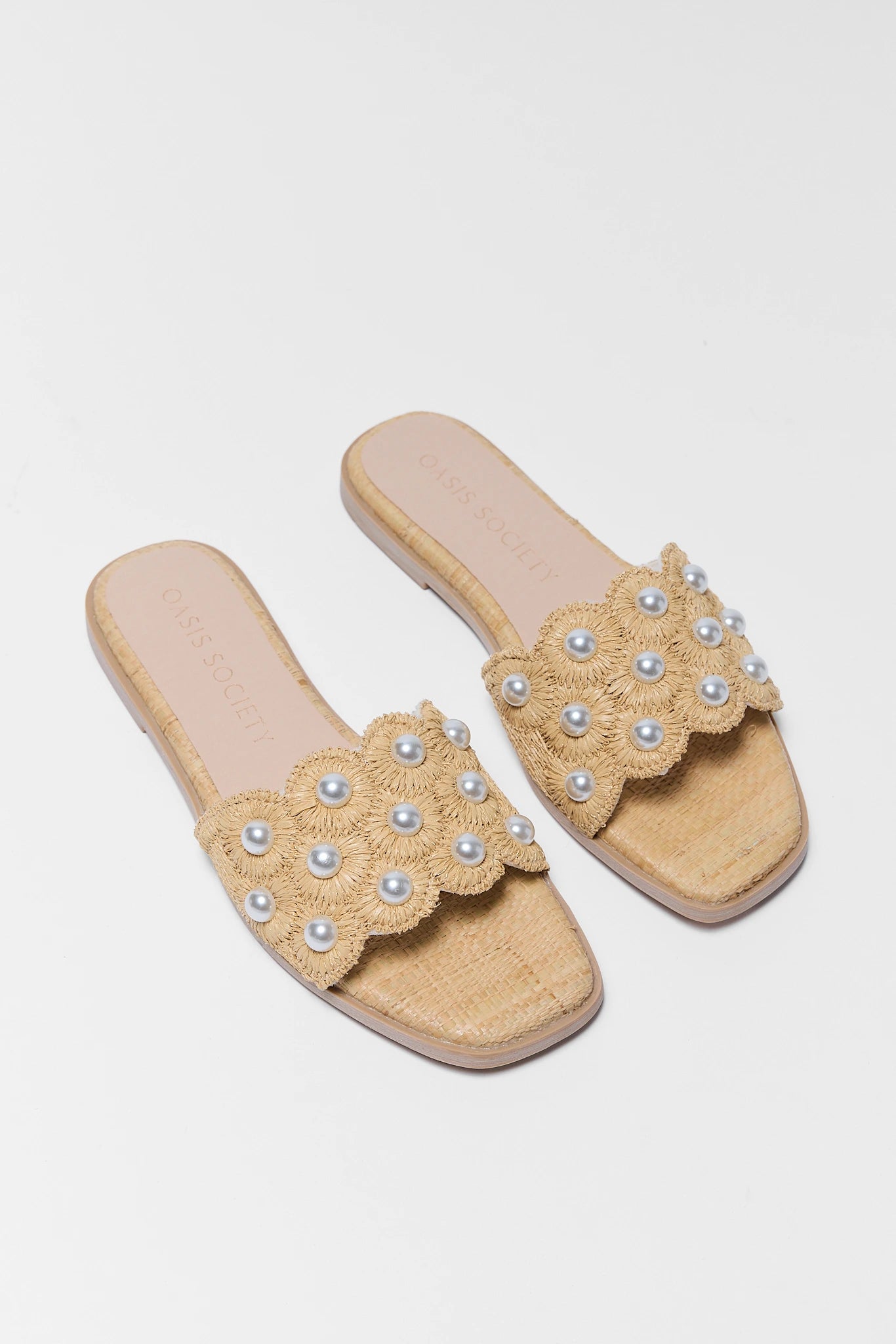 Beige sandals with pearl embellishments on a light gray background