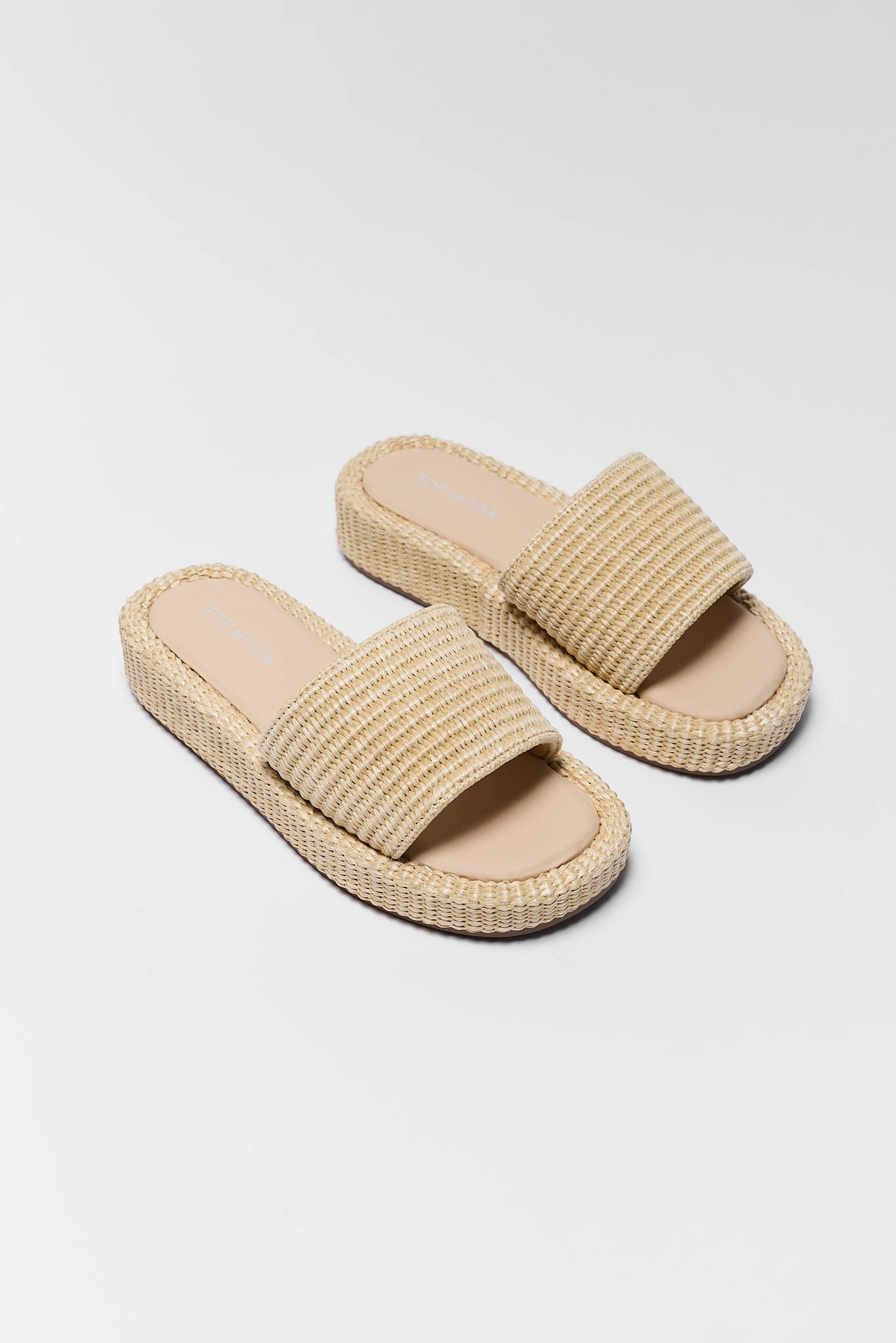 Pair of beige raffia woven sandals on a light gray background