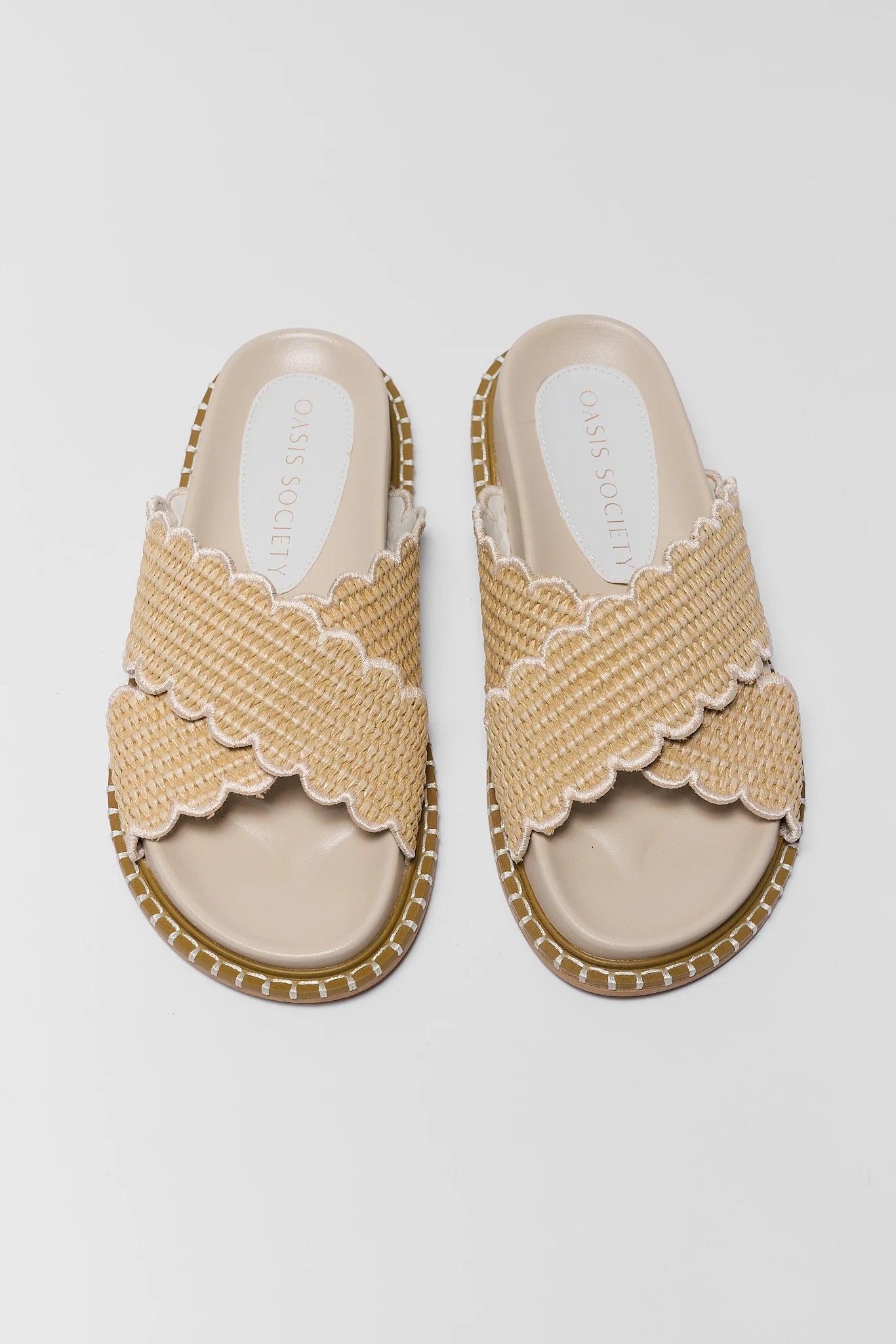 Pair of two beige sandals with scalloped edges on a light gray background
