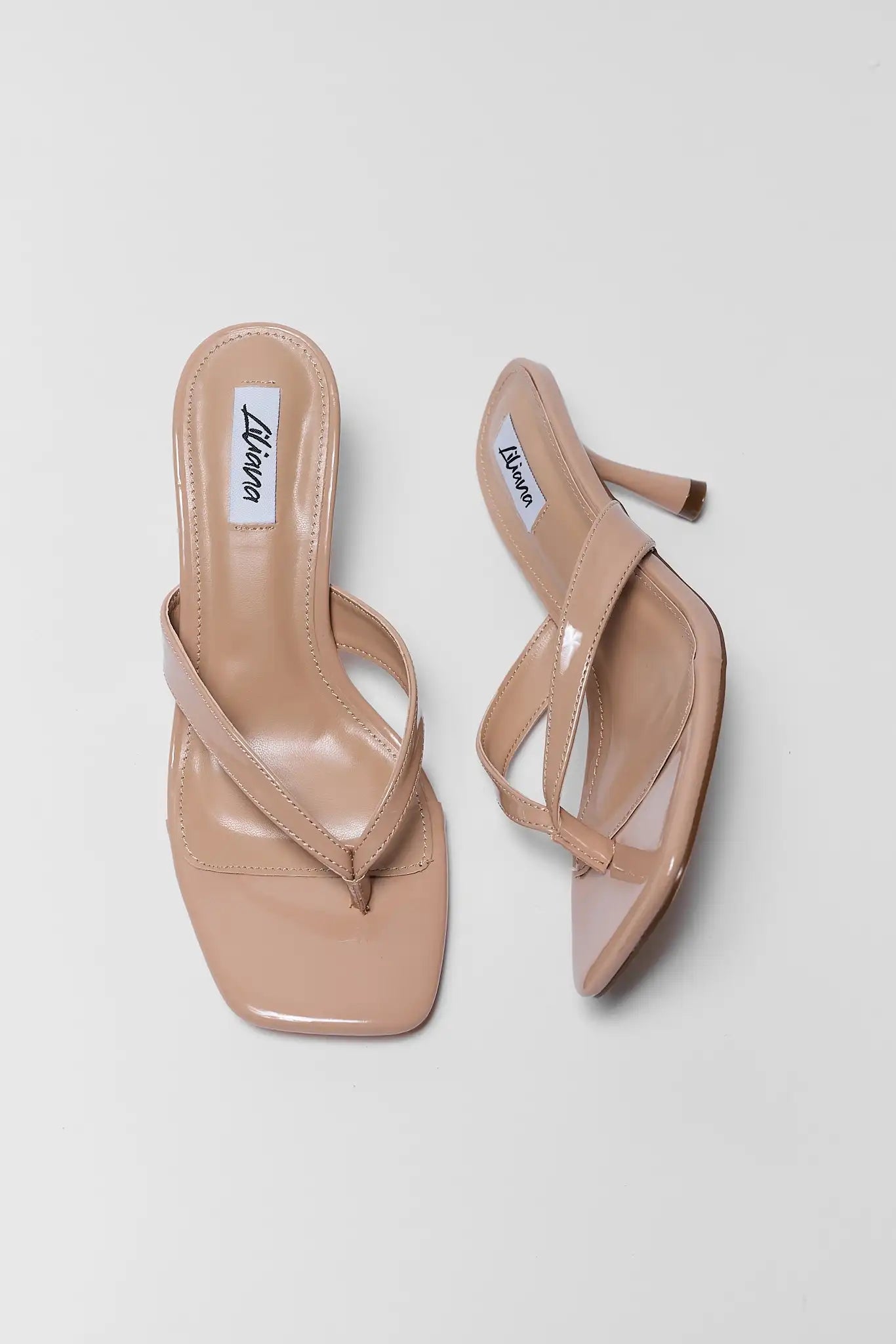 Pair of beige sandals with branding on a light gray background