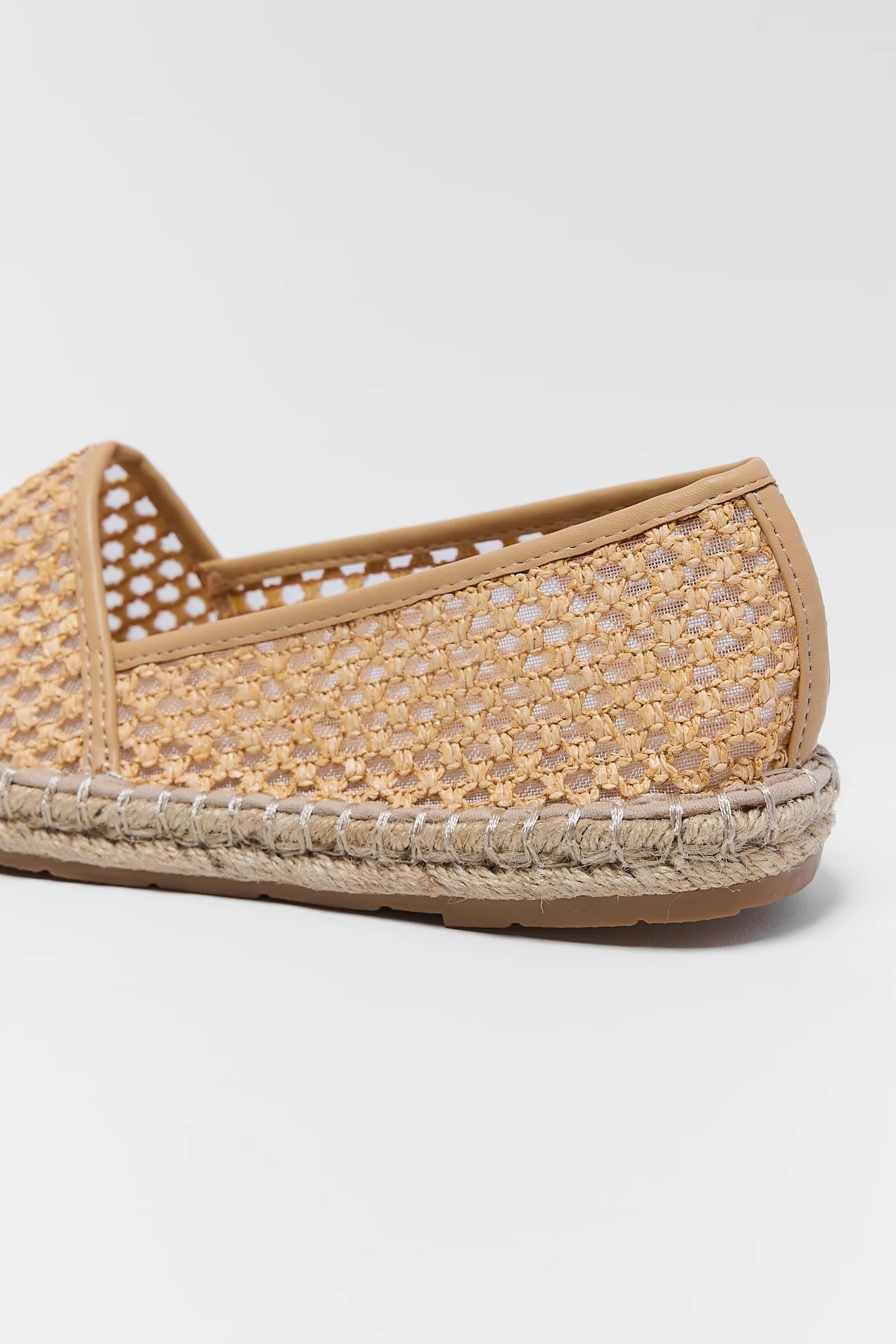 Beige espadrille shoe on a light gray background close up