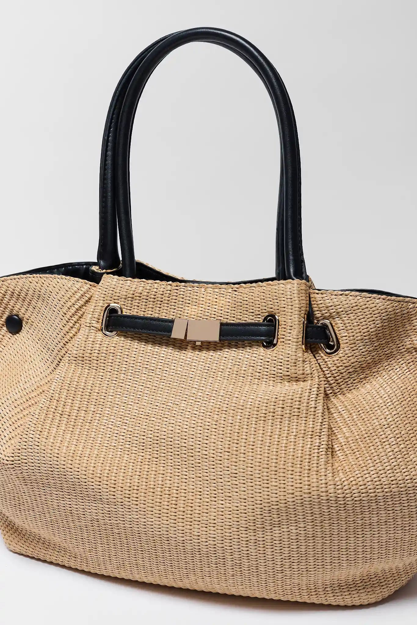 close up Beige straw handbag with black handles and trim on a light gray background