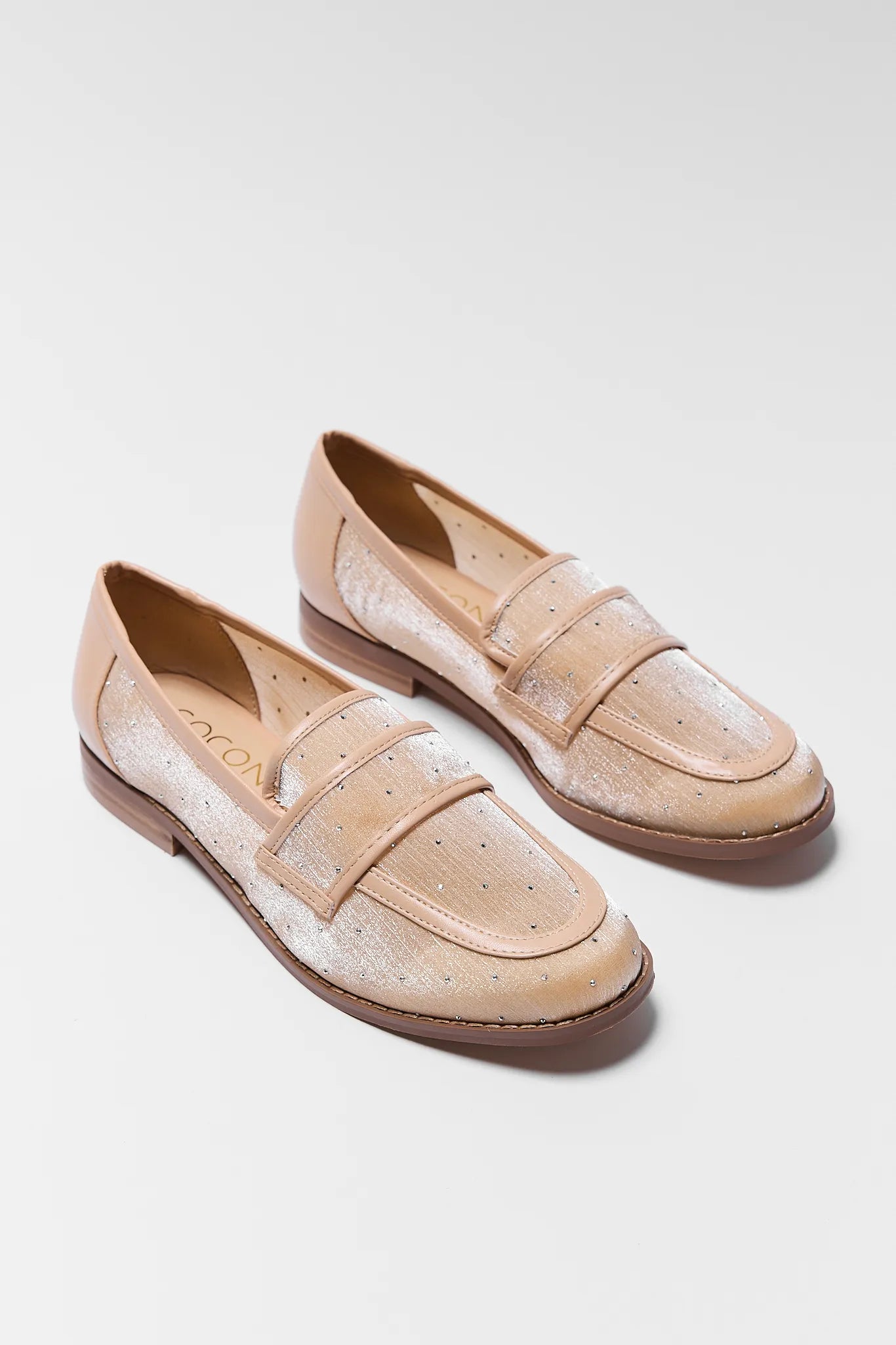 Pair of beige loafers on a light gray background