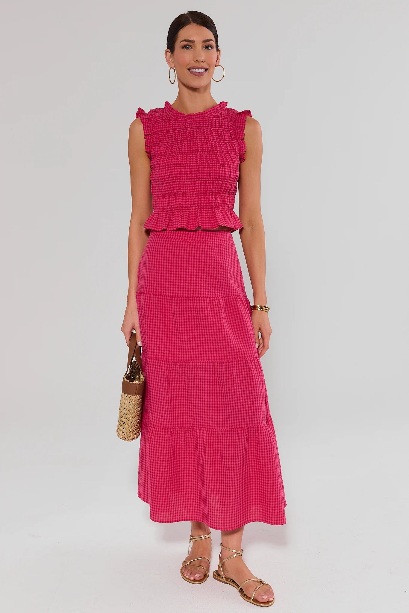Woman wearing a pink dress with ruffled top and checkered skirt on a white background