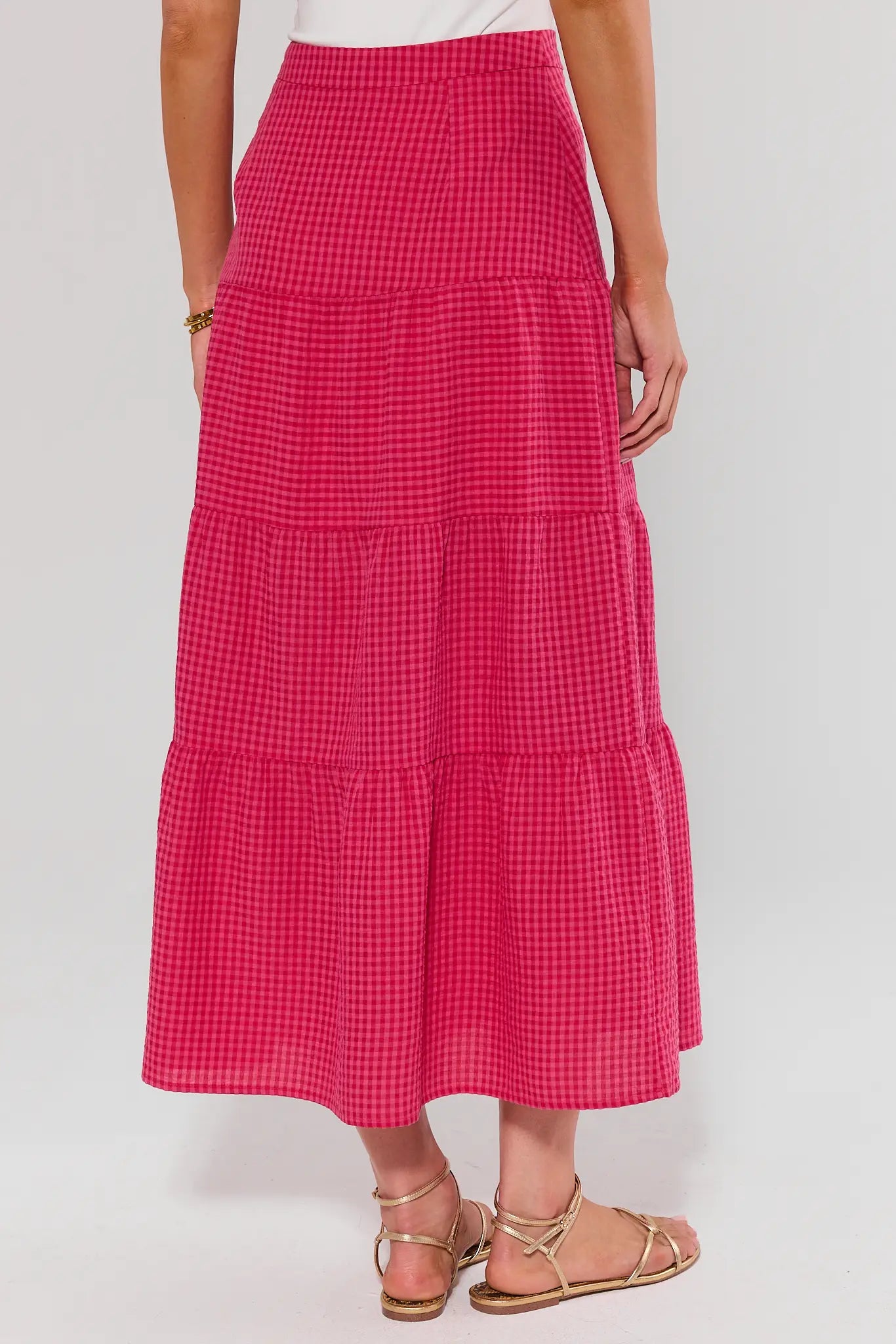 Person standing wearing a pink checkered skirt on a white background