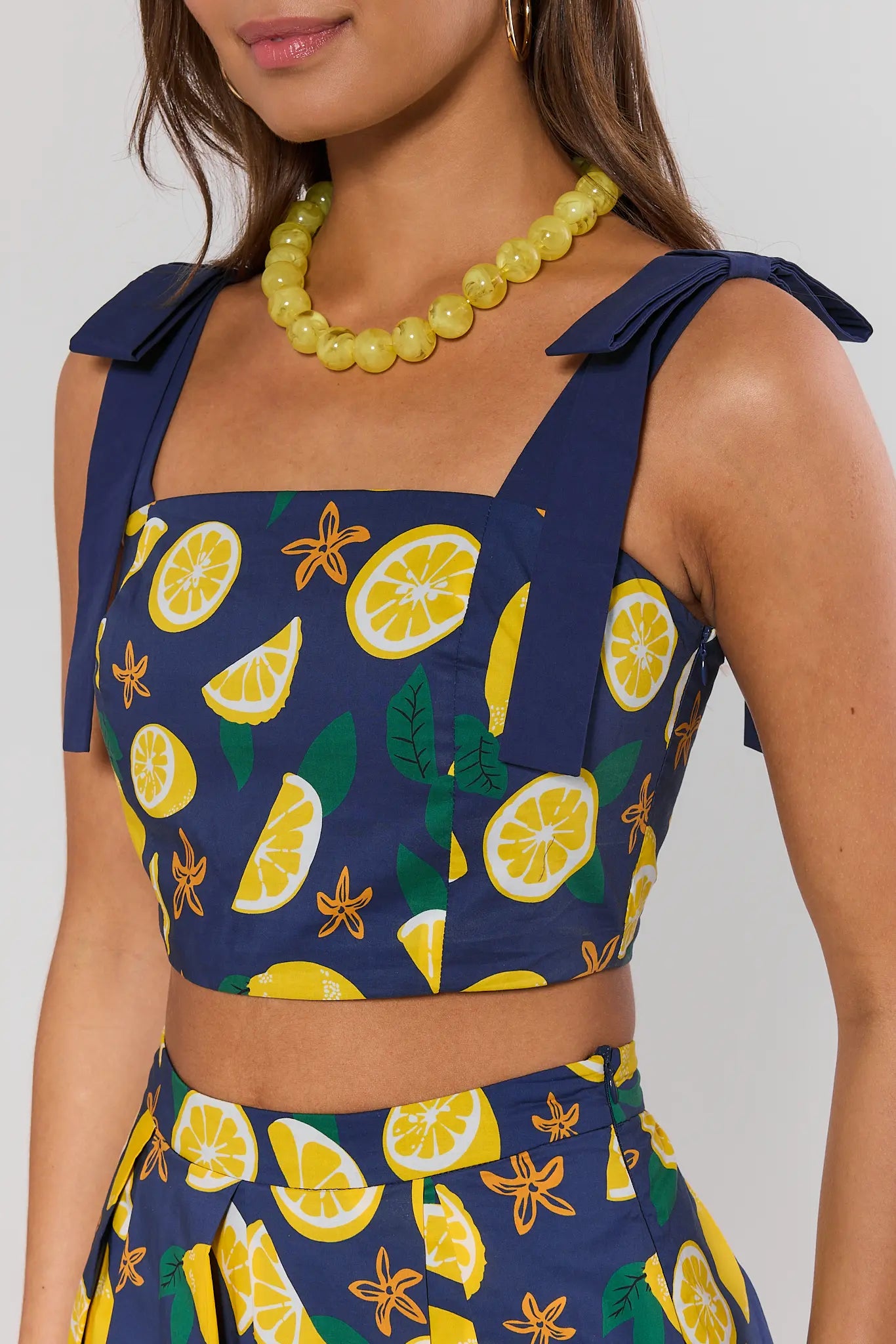 close up Navy blue top with lemon pattern worn by a model against a neutral background