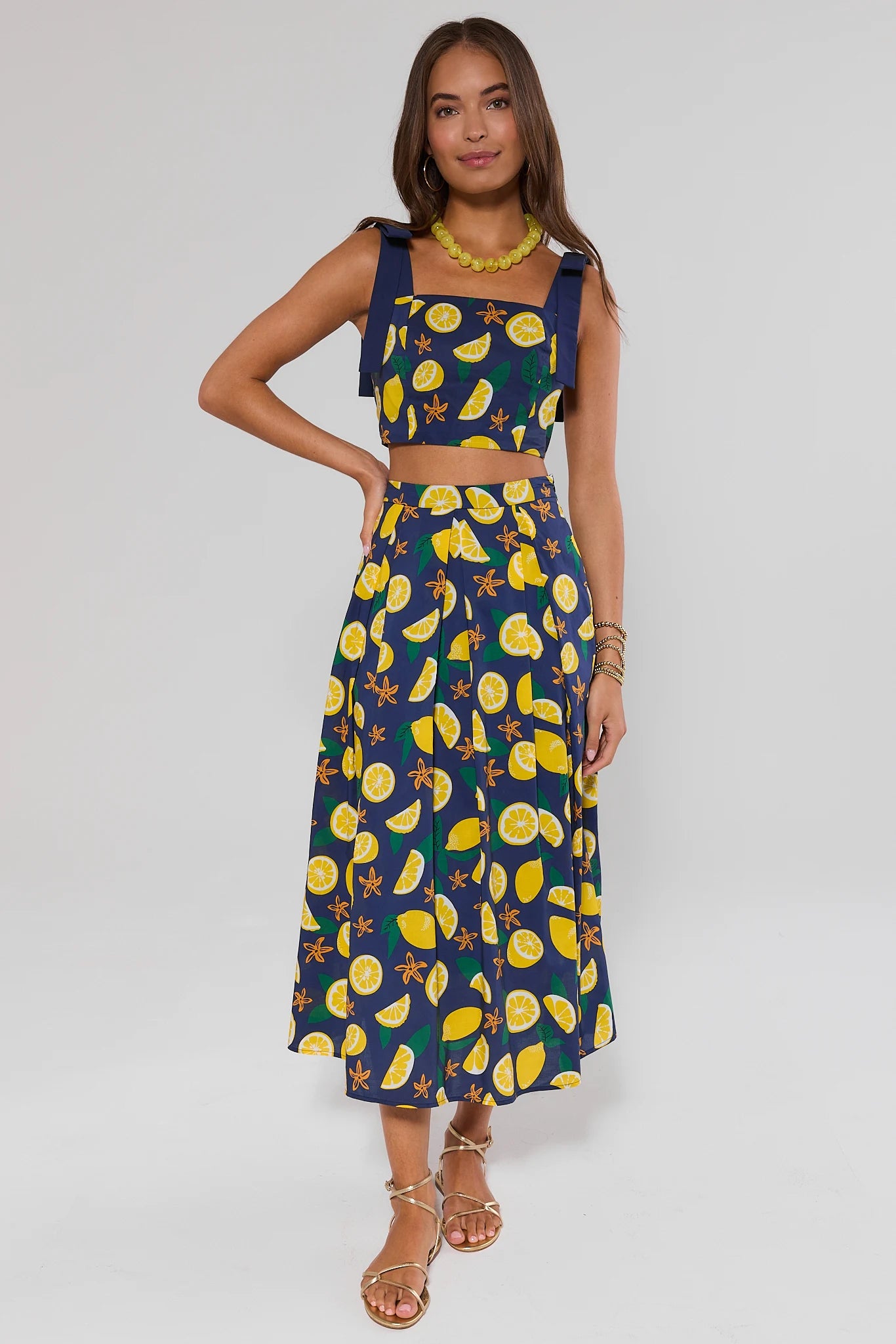 Woman wearing a navy blue top and skirt with yellow lemon pattern on a background