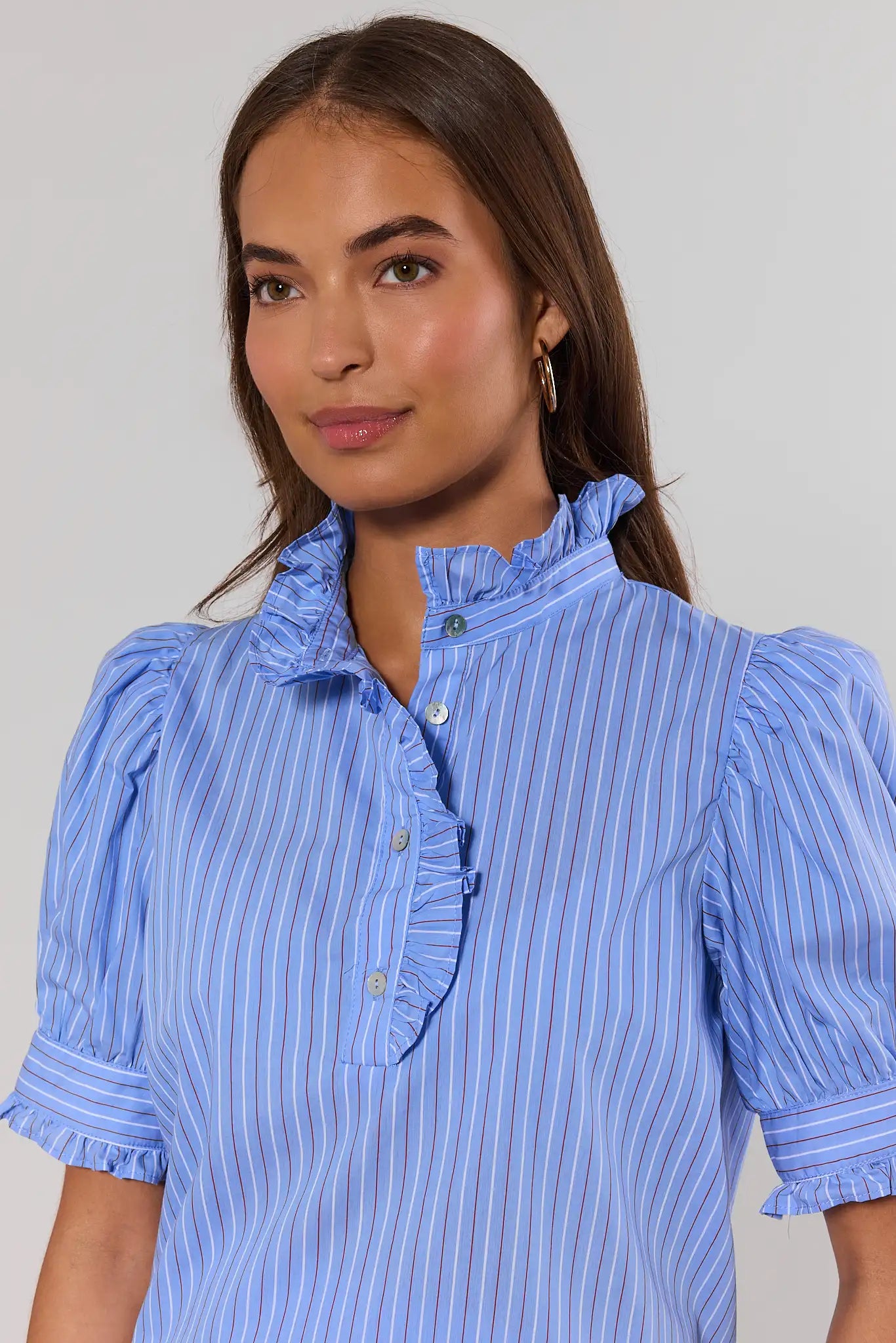close up Woman wearing a blue striped dress with ruffled collar and puff sleeves against a plain background
