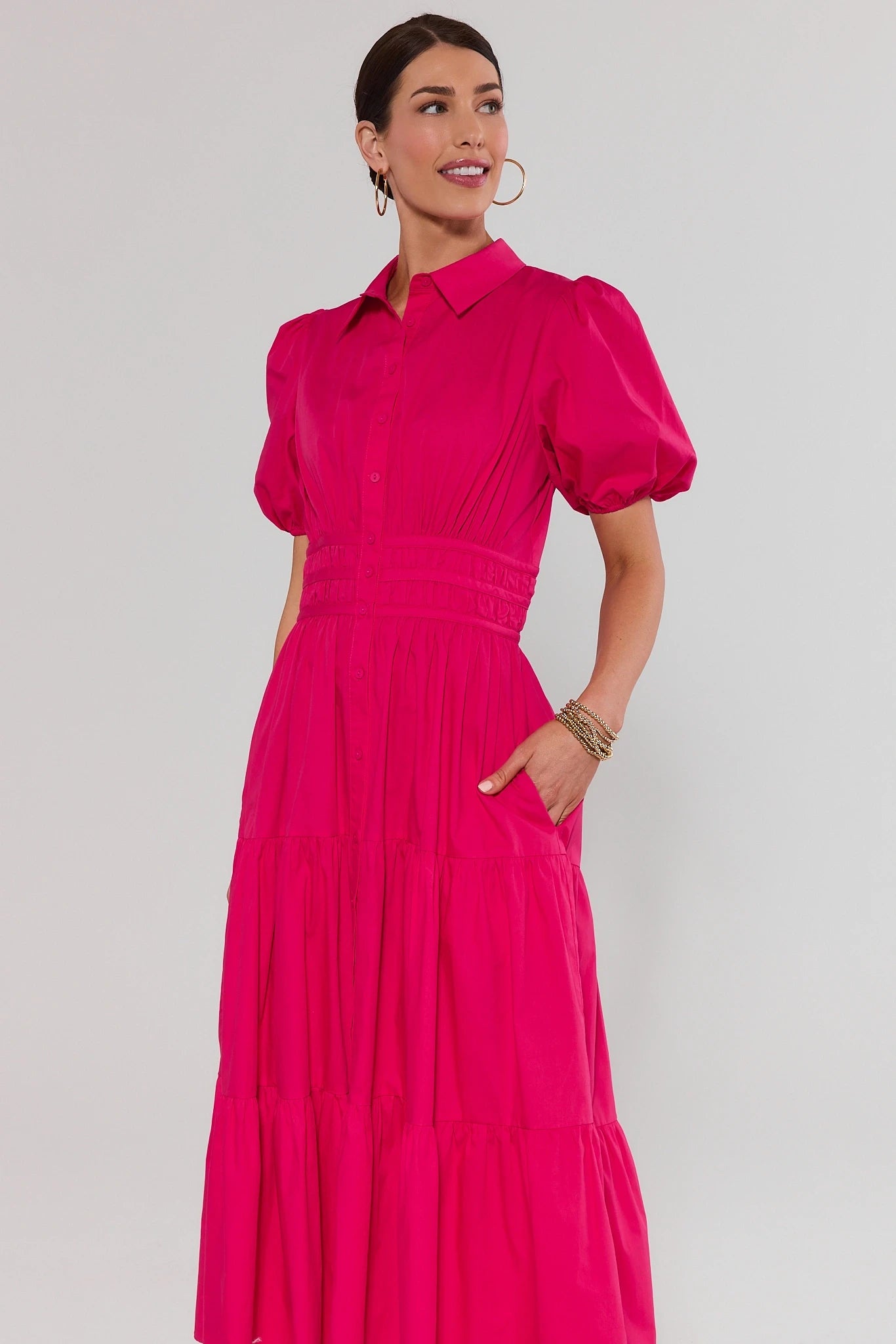 Woman wearing a bright pink dress against a plain background