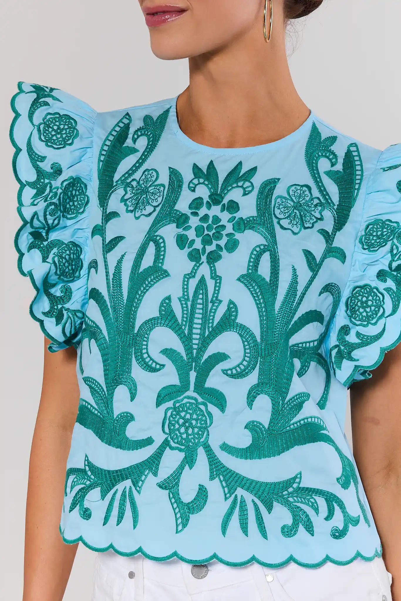 close up Light blue blouse with green floral lace details on a plain background