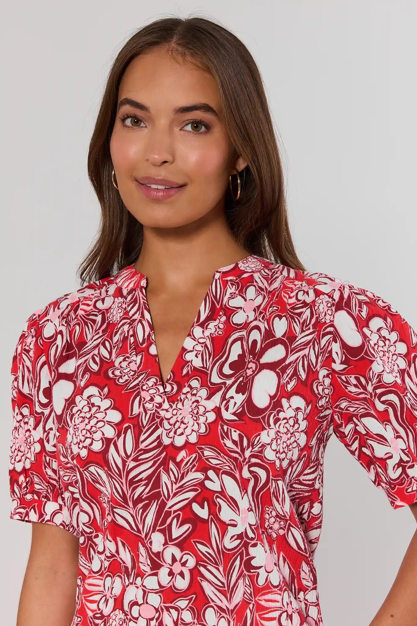 close up Woman wearing a red floral patterned dress against a plain background
