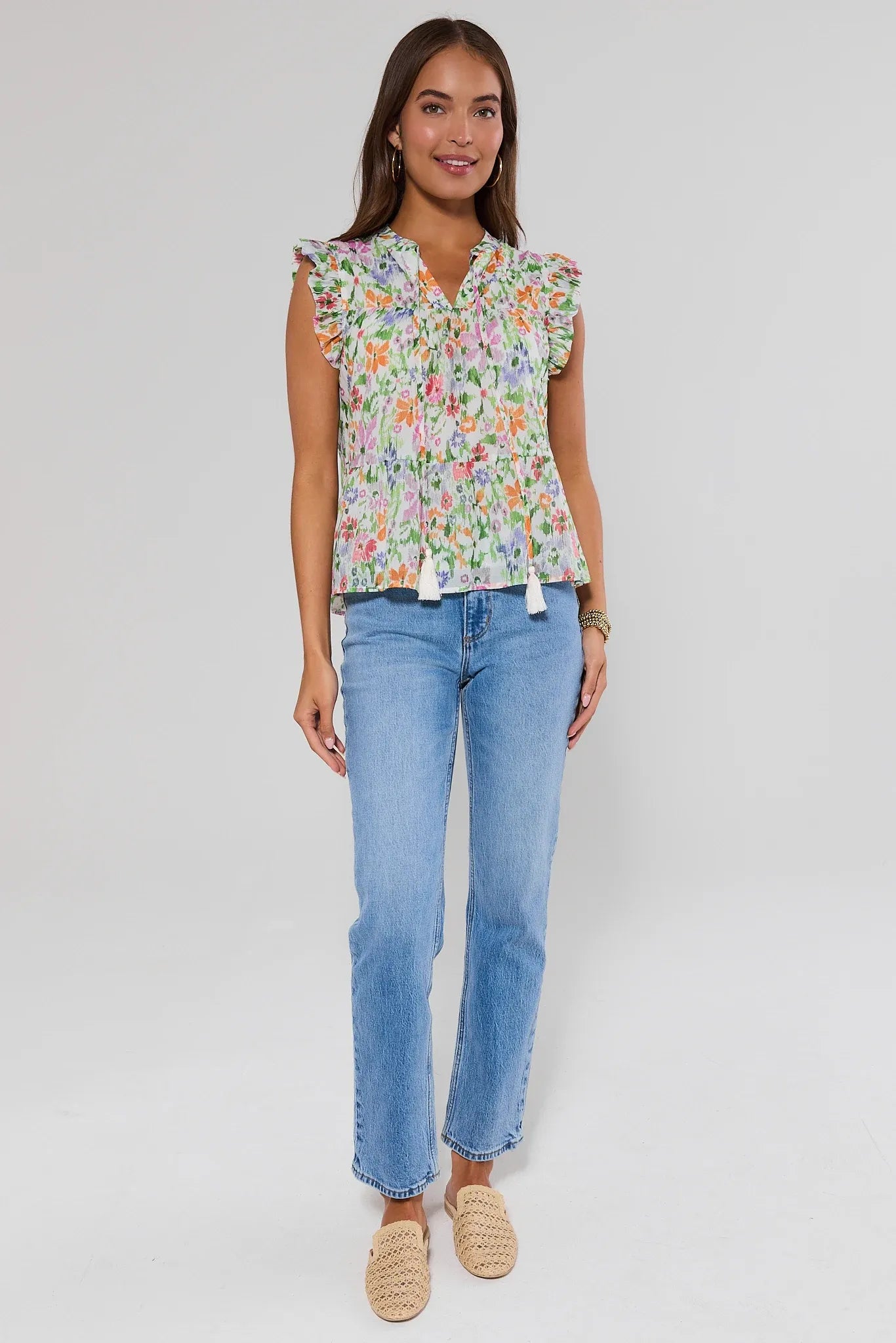Woman wearing a floral faye blouse and blue jeans on a white background