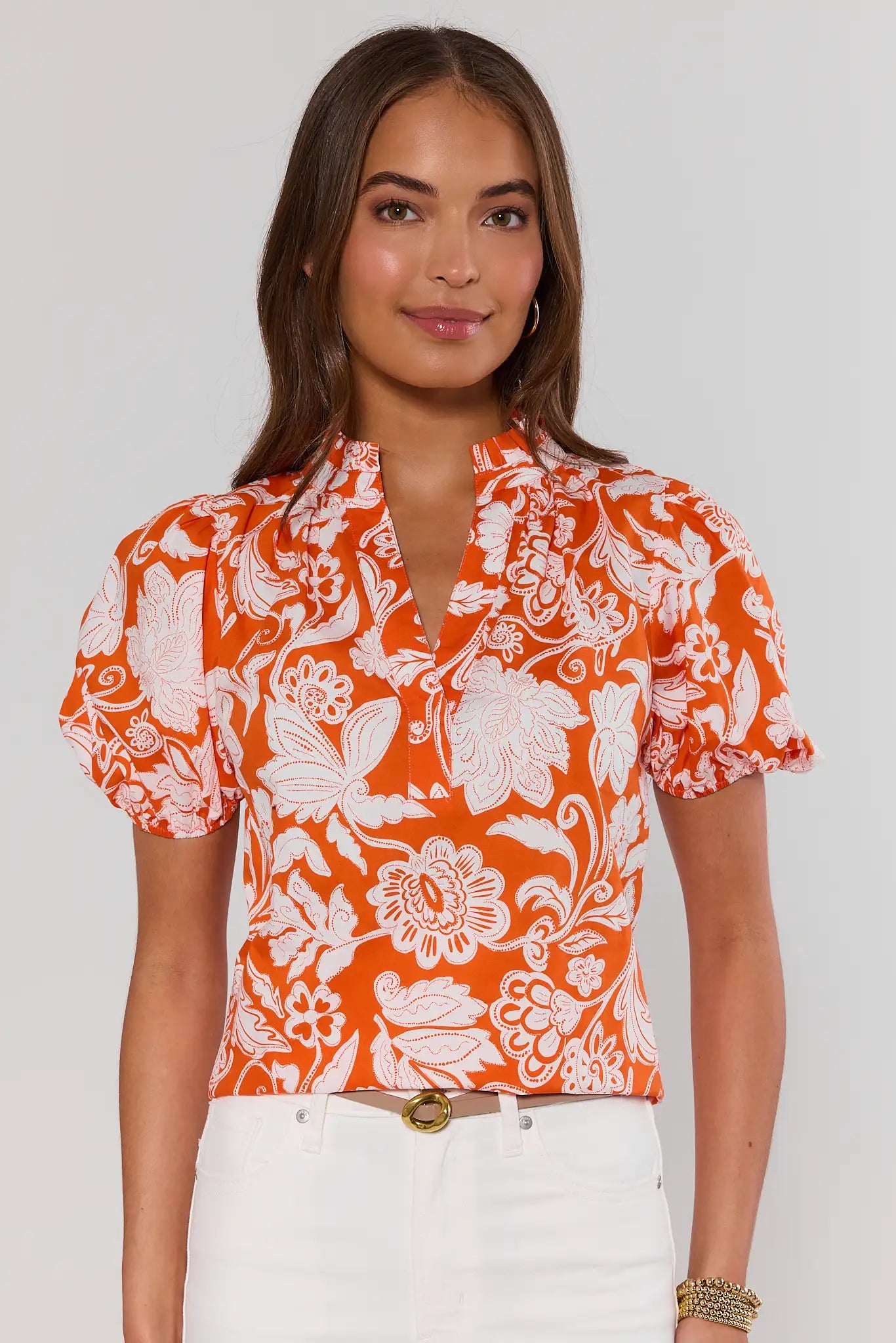 Woman wearing an orange rosanna floral blouse against a white background