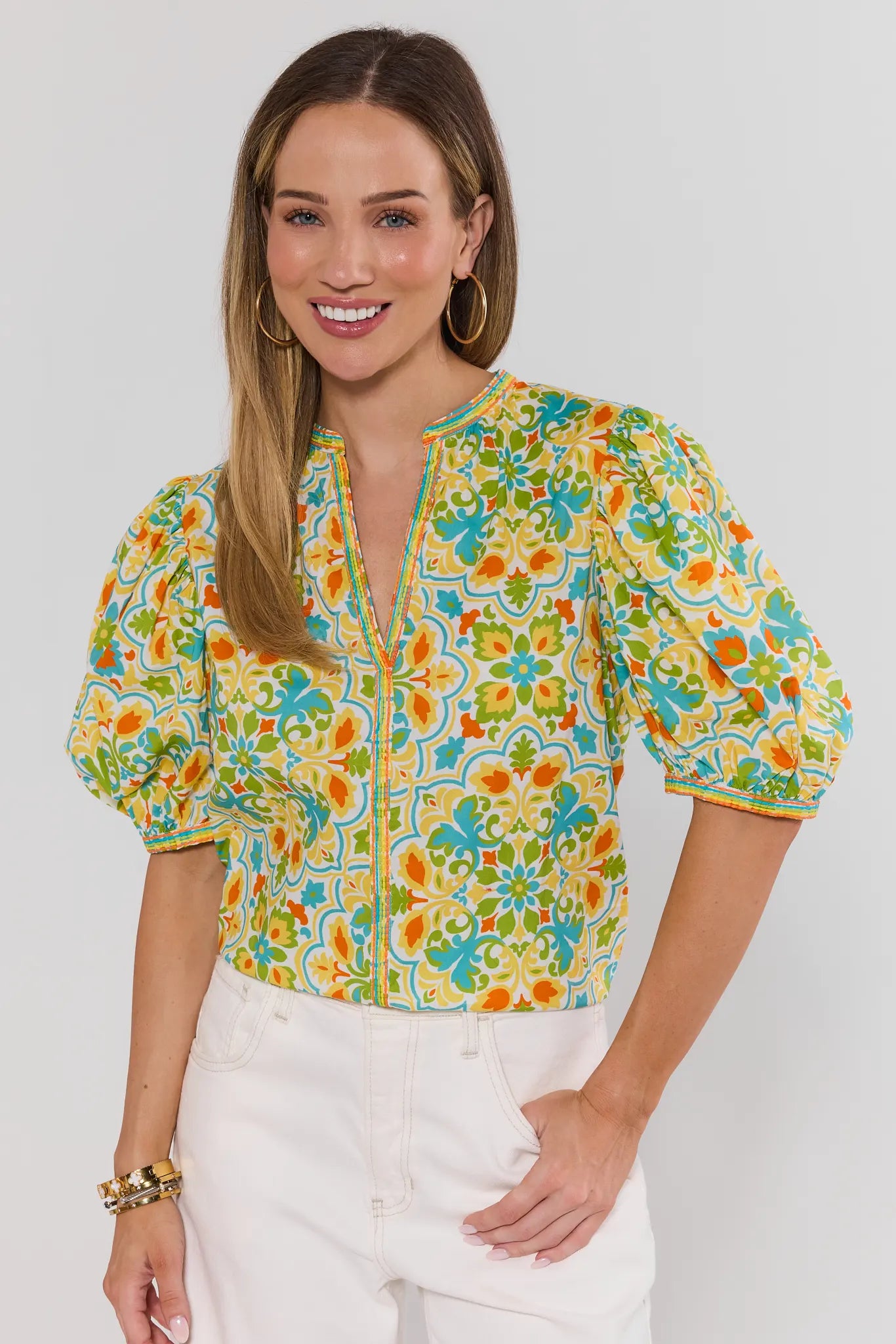 Woman wearing a colorful floral blouse with puff sleeves on a white background