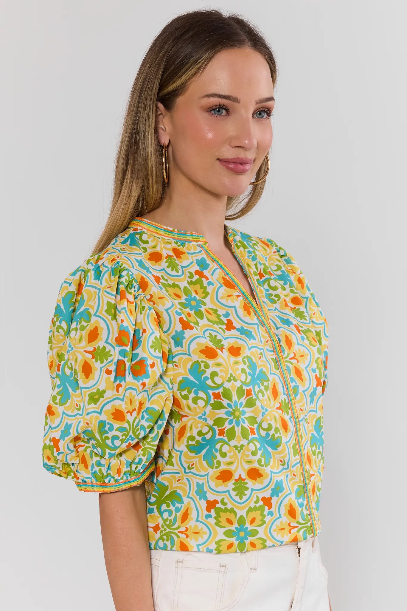 side shot Woman wearing a colorful floral blouse against a plain background
