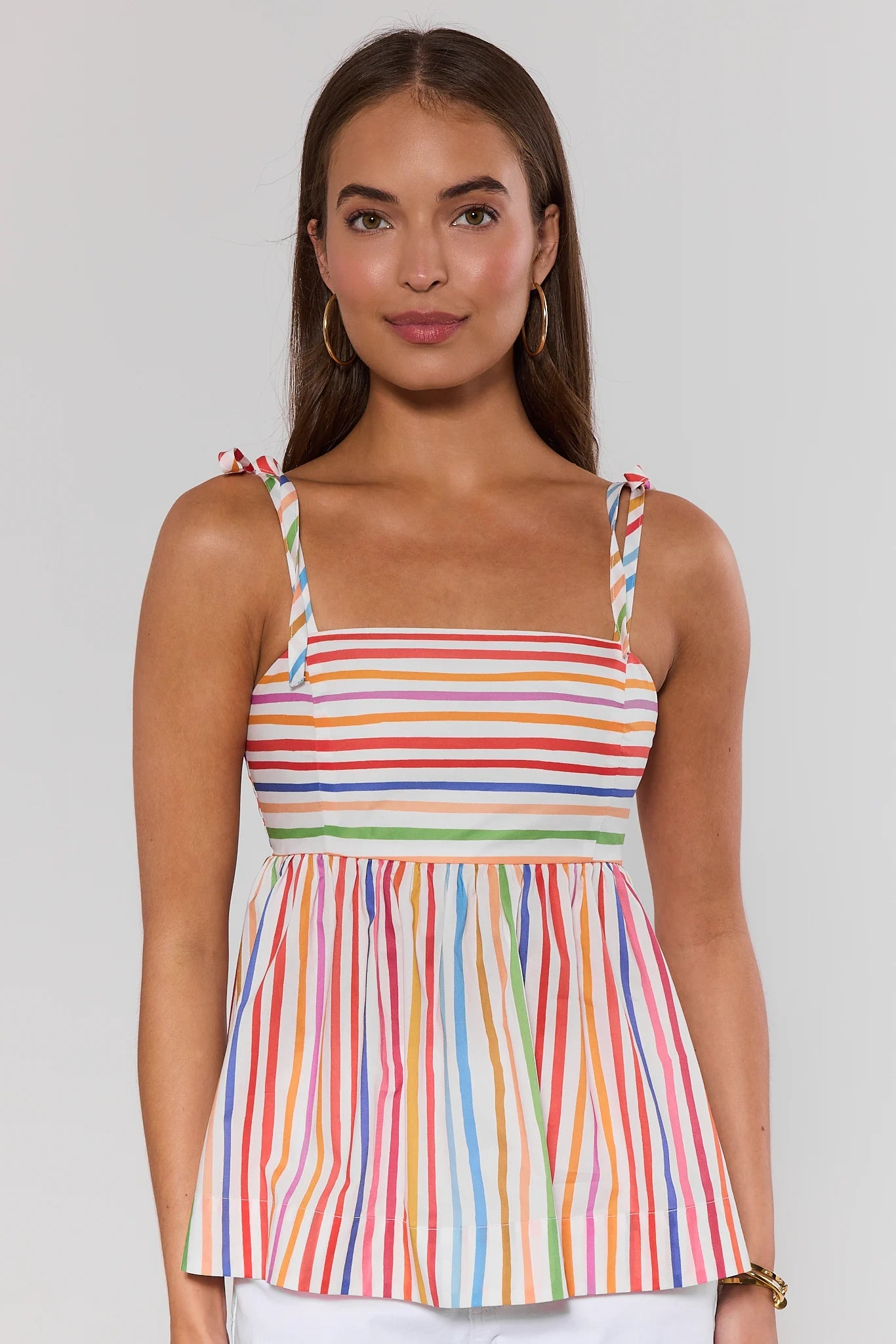 Woman wearing a colorful striped dress against a plain background