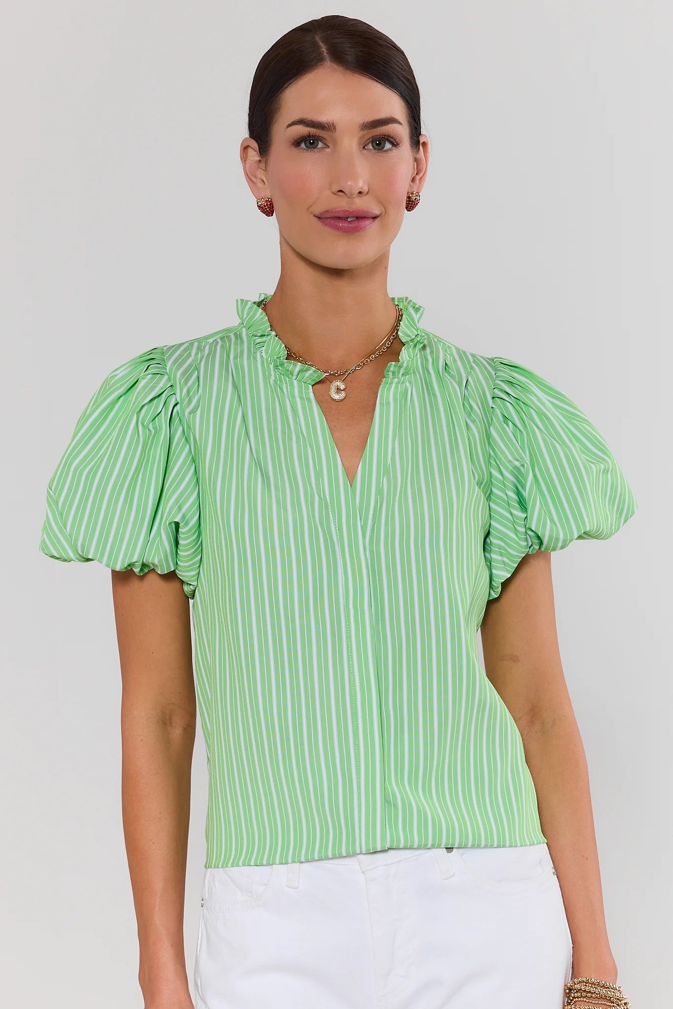 Woman wearing a green and white striped blouse against a plain background