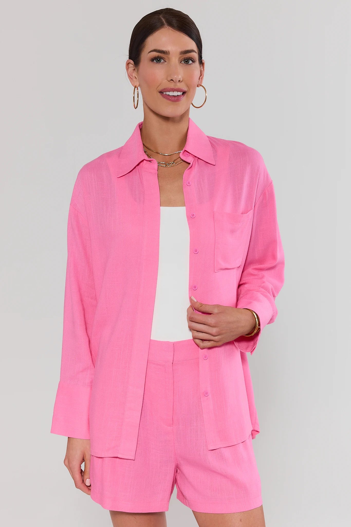 Woman wearing a pink outfit with a matching top and shorts on a plain background