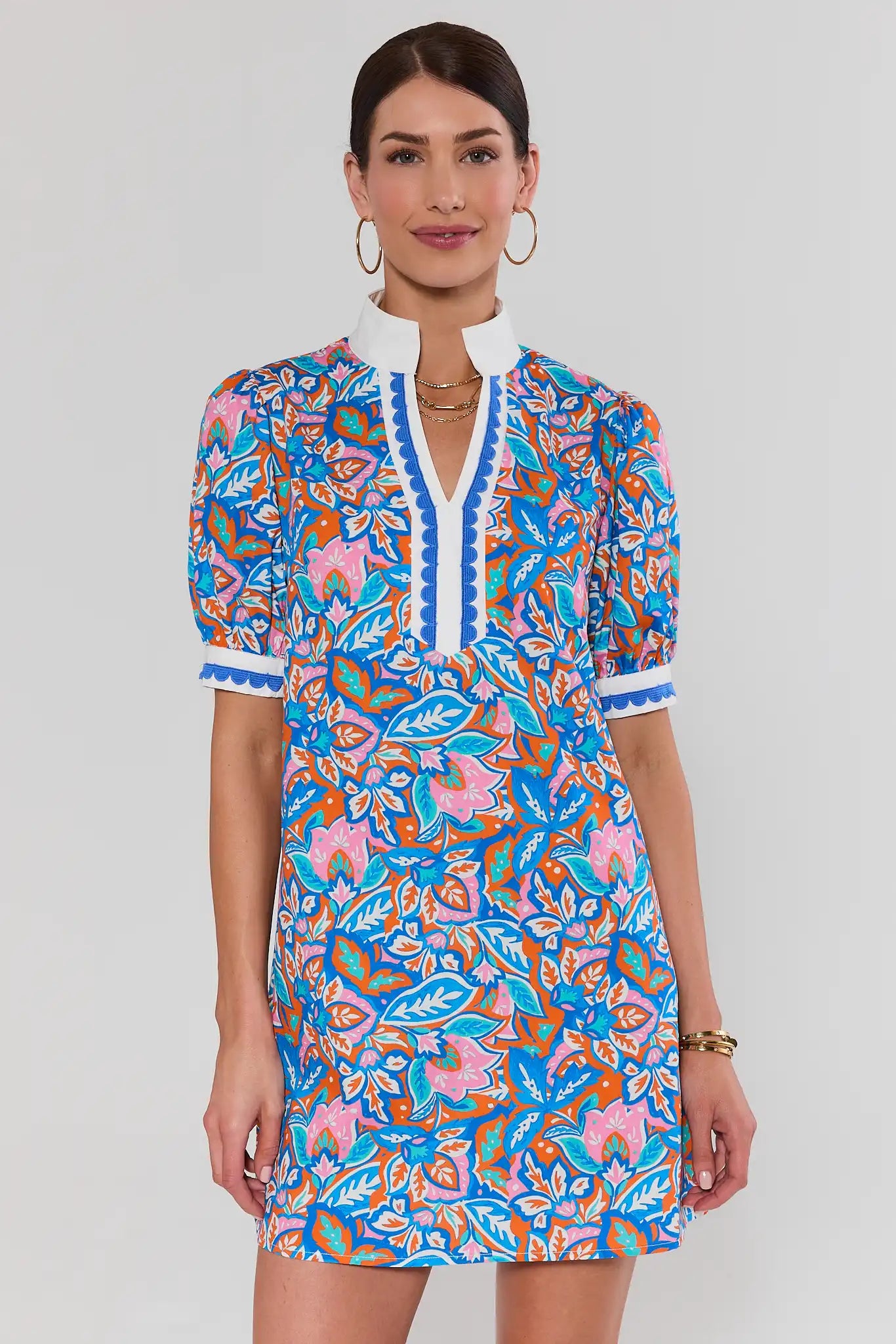 Woman wearing a colorful patterned dress standing on a plain background
