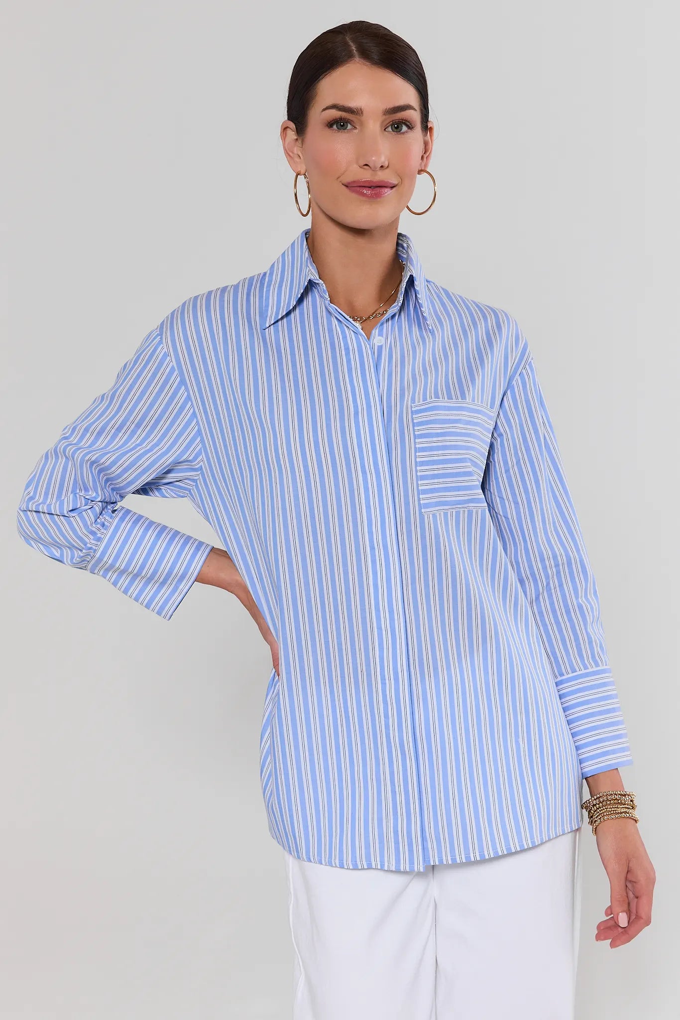 Woman wearing a blue and white striped button up shirt against a plain background