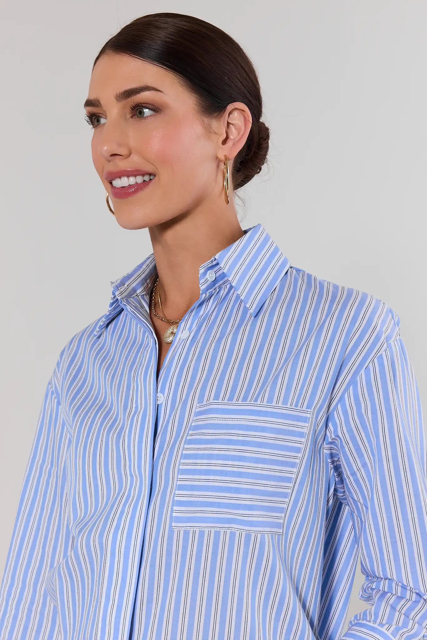 close up Woman wearing a blue and white striped shirt against a plain background