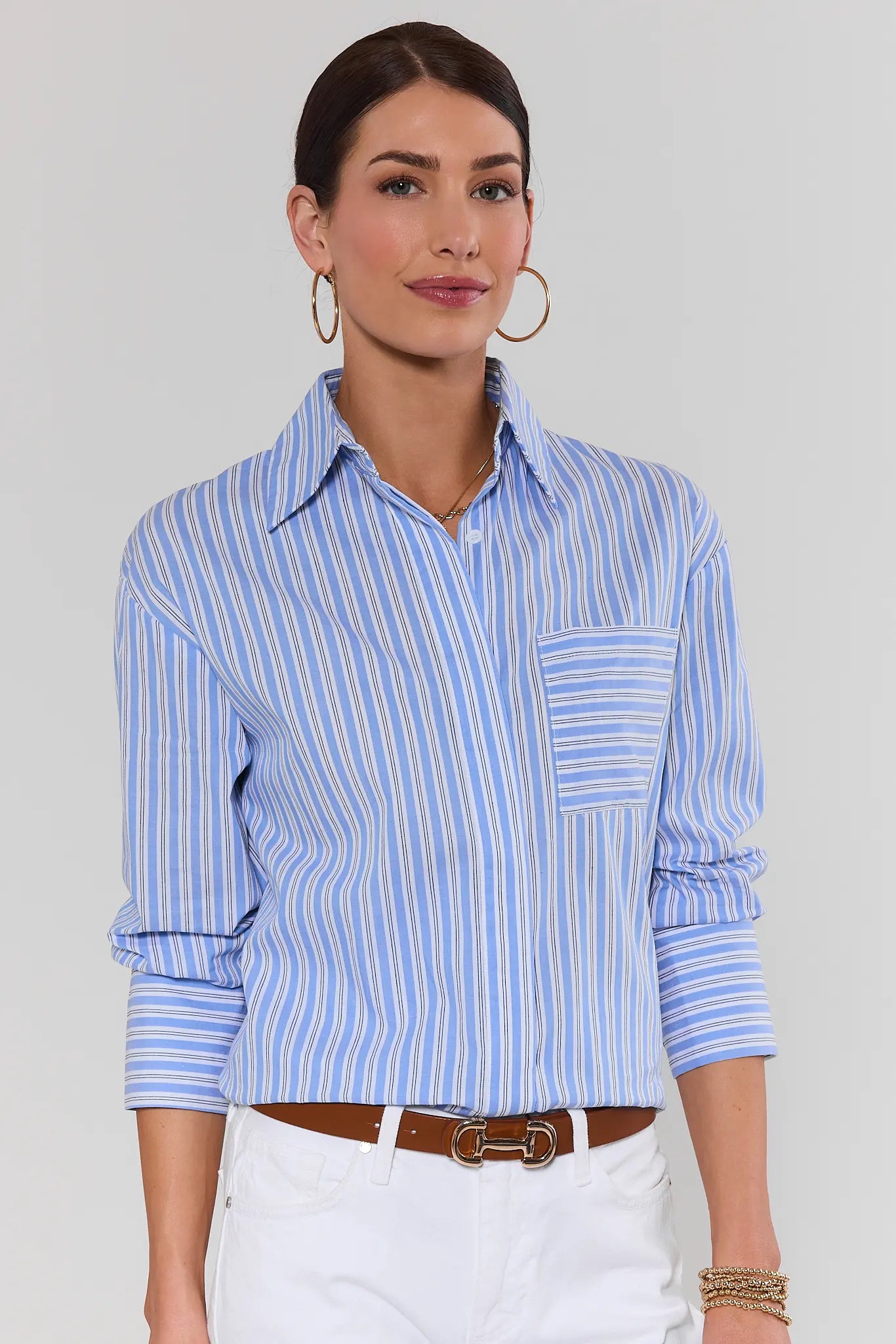 Woman wearing a blue and white striped shirt with a plain background