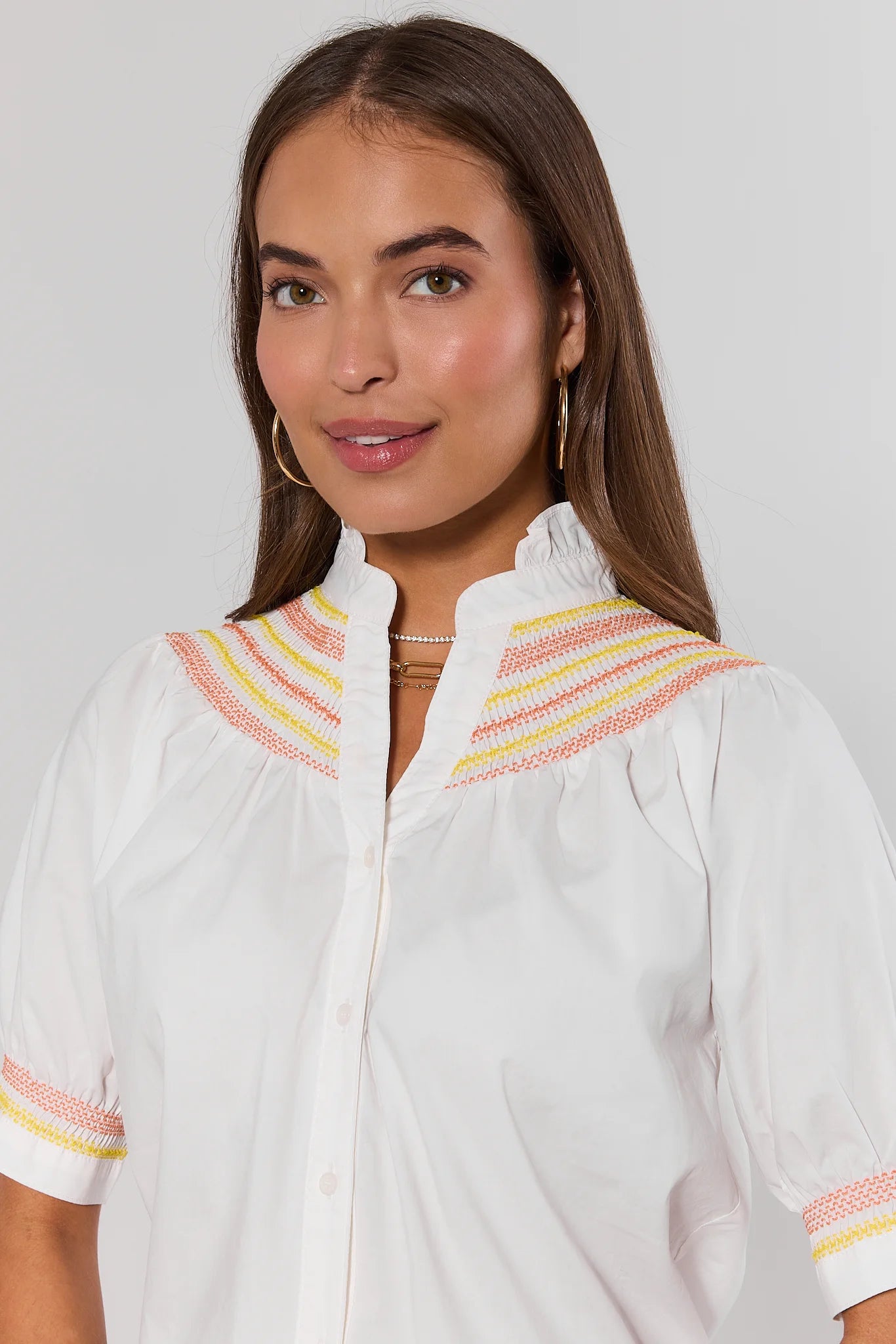 close up Woman wearing a white blouse with colorful trim on a plain background