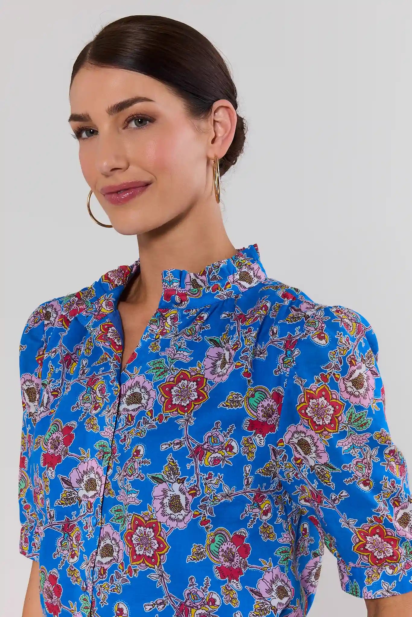 close up Woman wearing a blue floral blouse against a white background