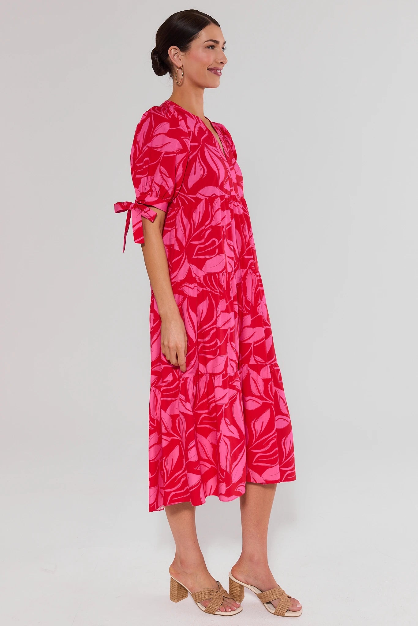 side shot Woman wearing a pink leaf-patterned dress on a white background