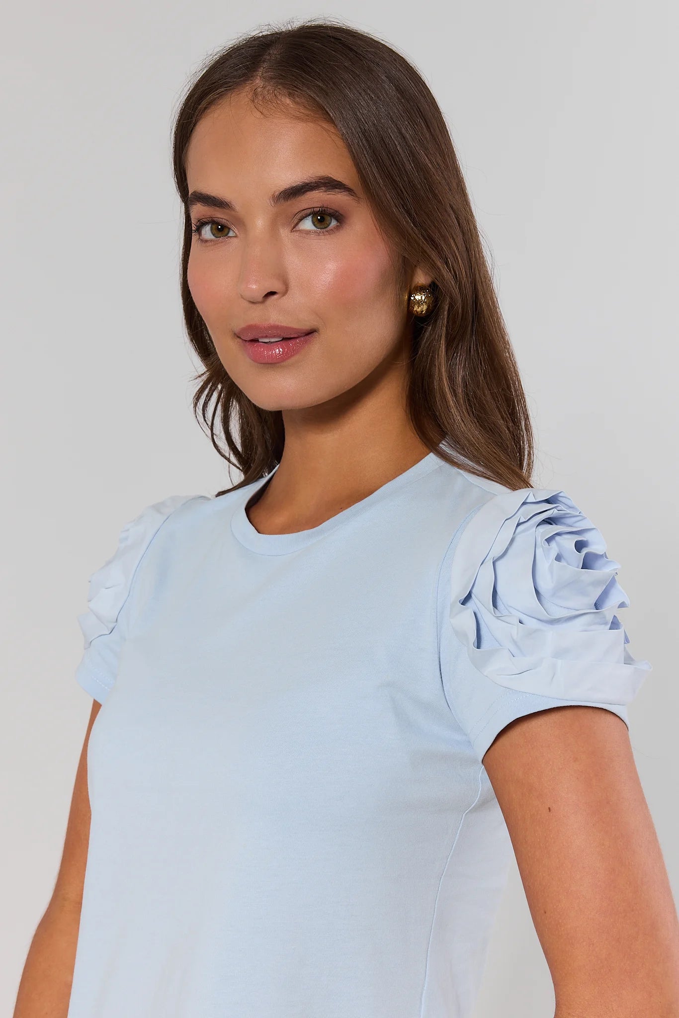 close up Woman wearing a light blue top with ruffled sleeves against a plain background