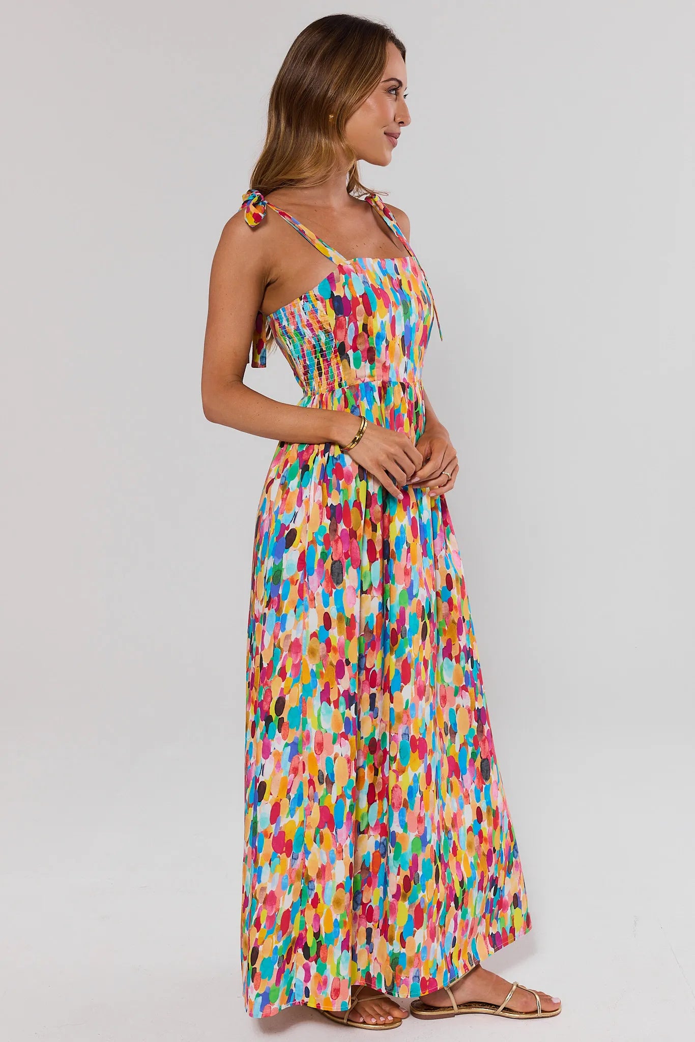 side shot Woman wearing a colorful patterned dress on a plain background