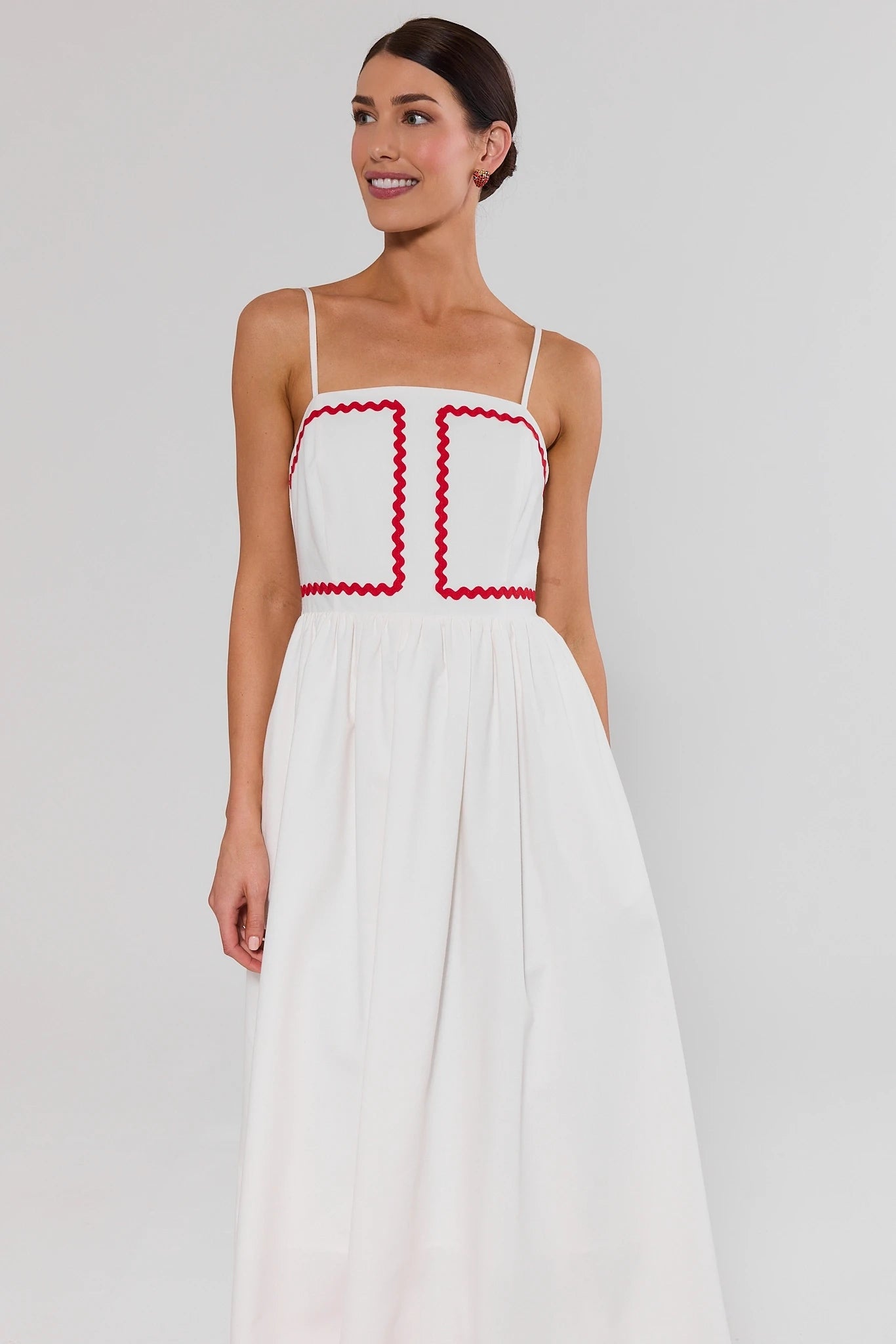 Woman wearing a white dress with red accents on a plain background