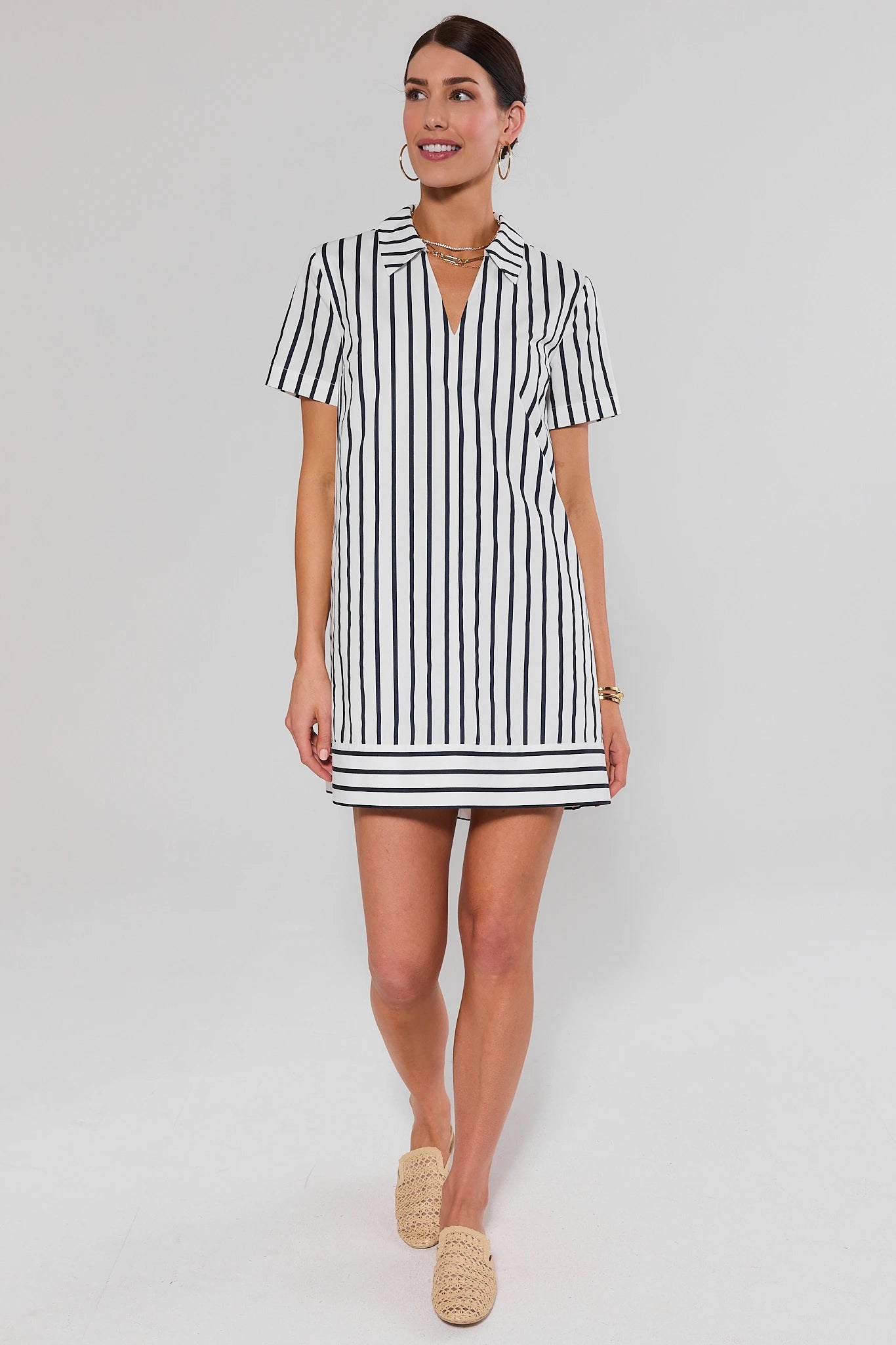 Woman standing wearing a black and white striped dress on a plain background