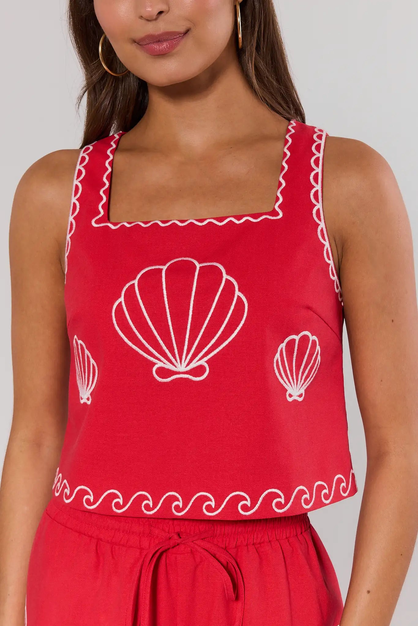 close up Red sleeveless top with white shell designs on a plain background