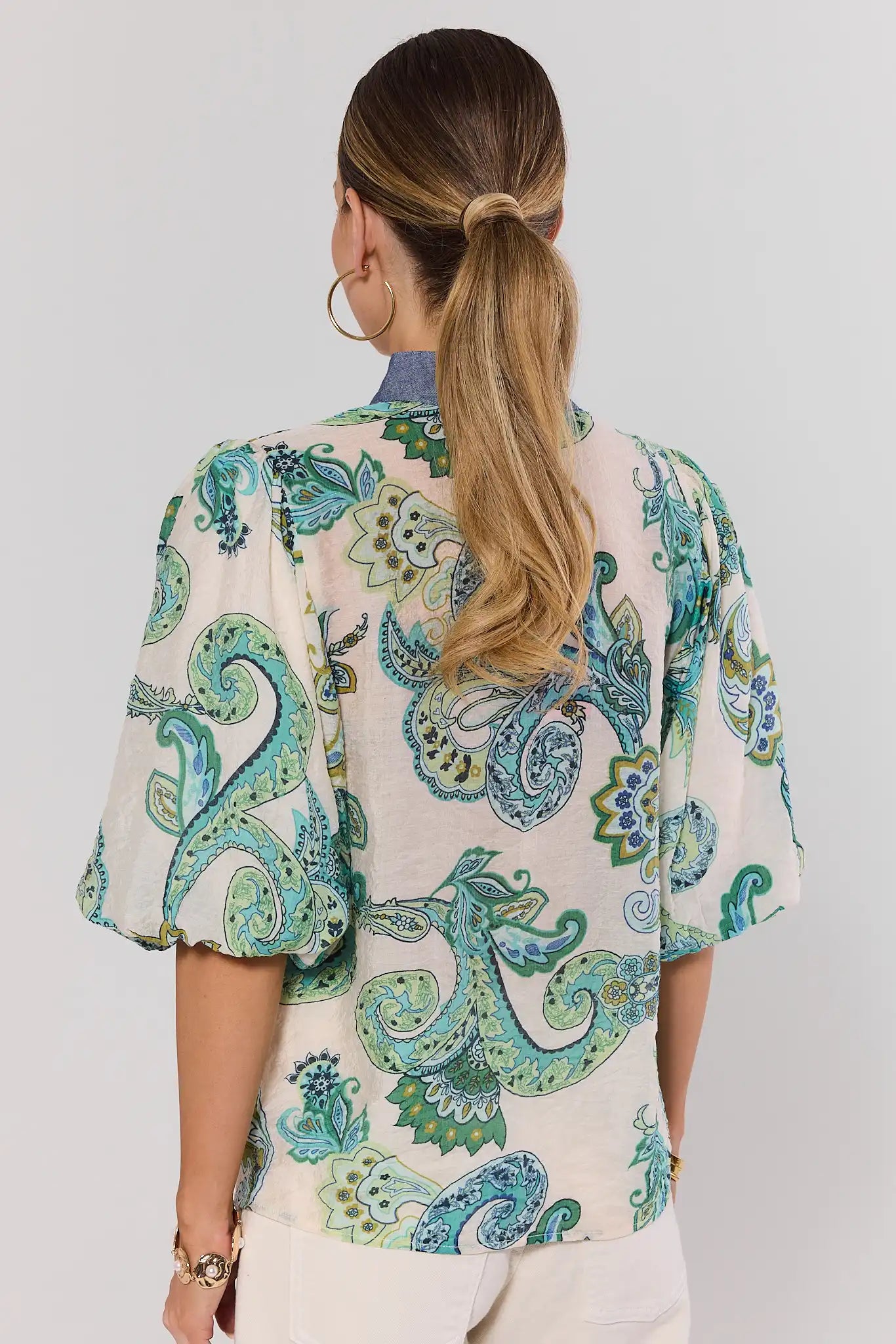 Woman wearing a patterned auriela blouse with a plain background