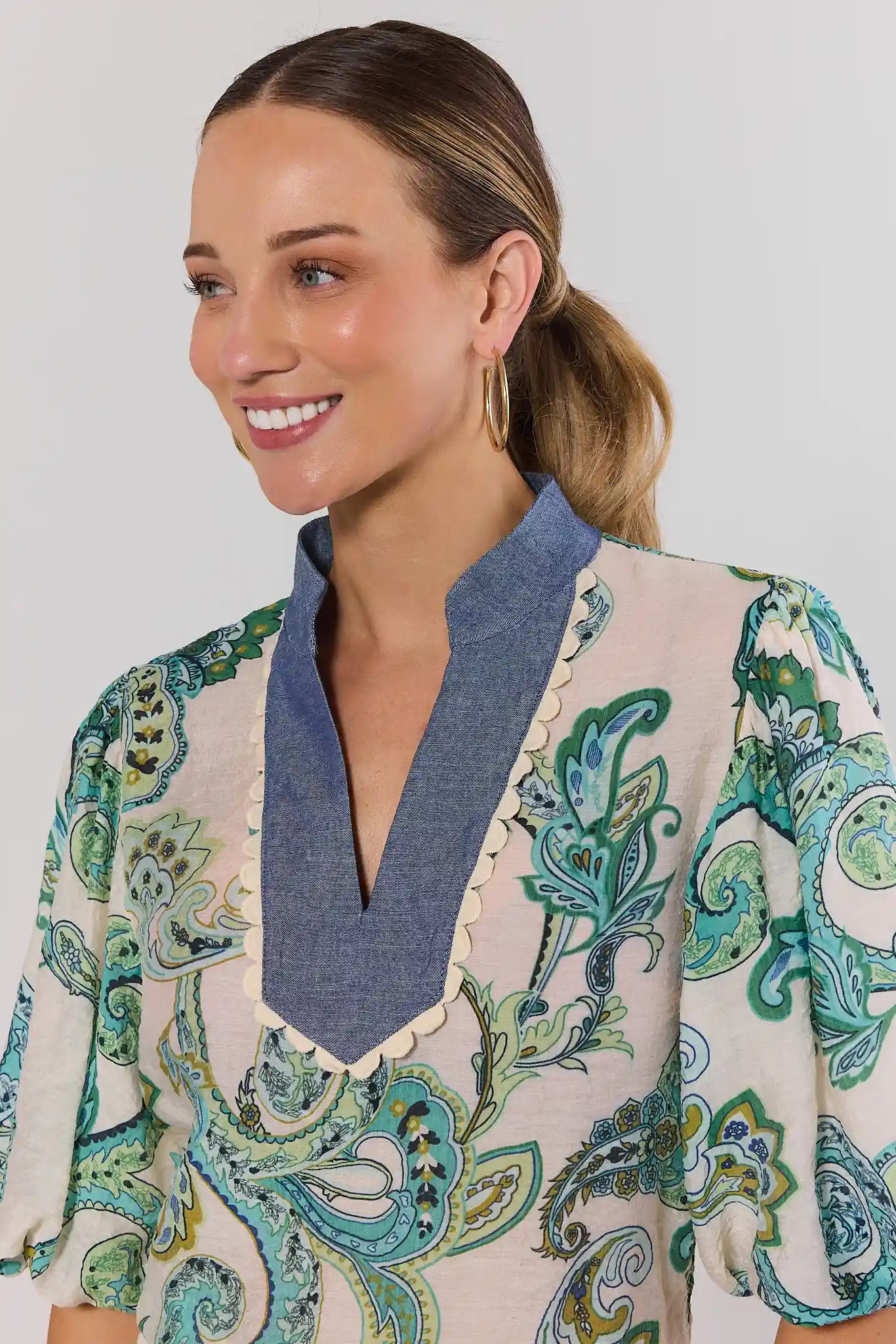 close up Woman wearing a patterned top with a blue collar against a plain background