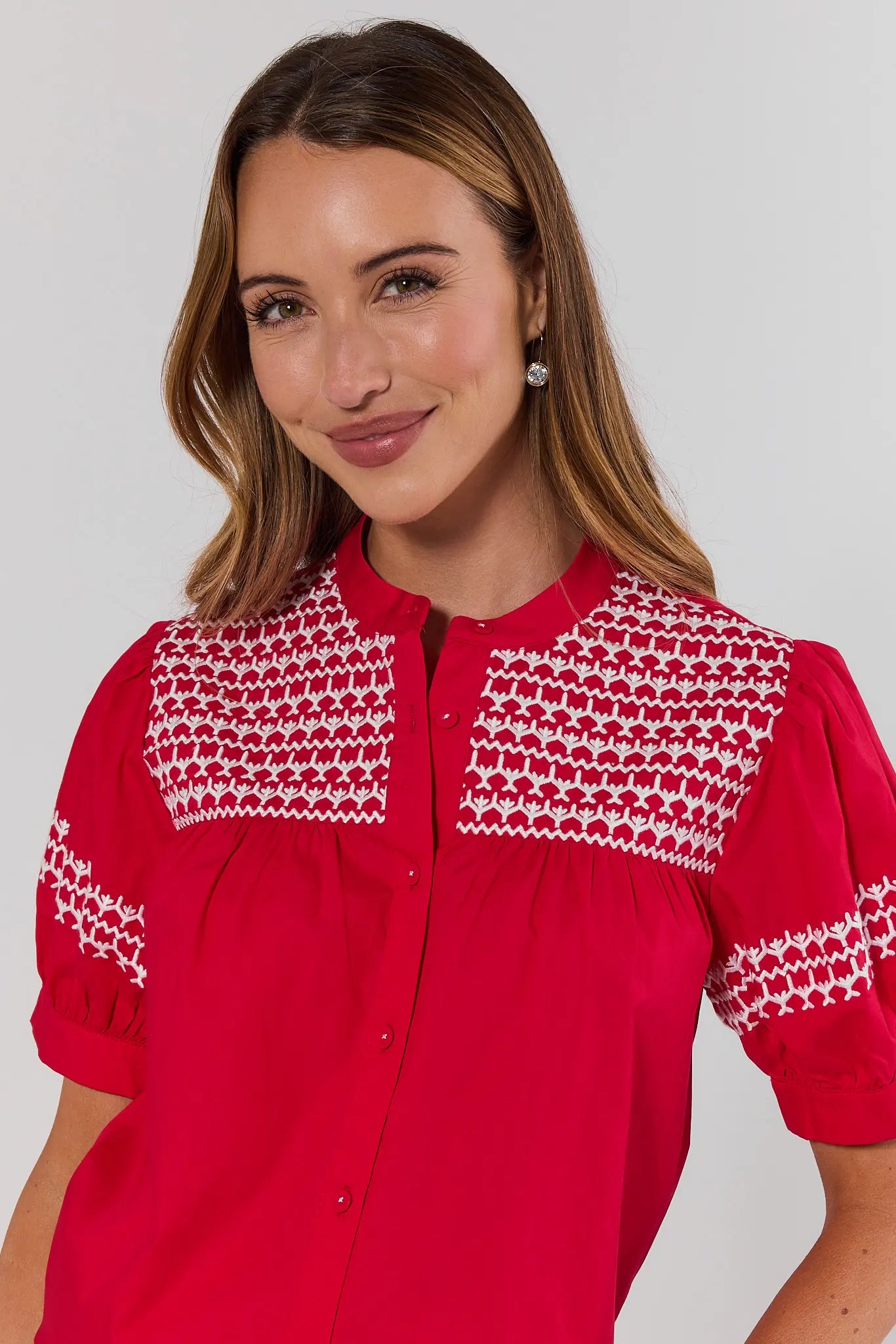 close up Woman wearing a red blouse with white patterns on a plain background