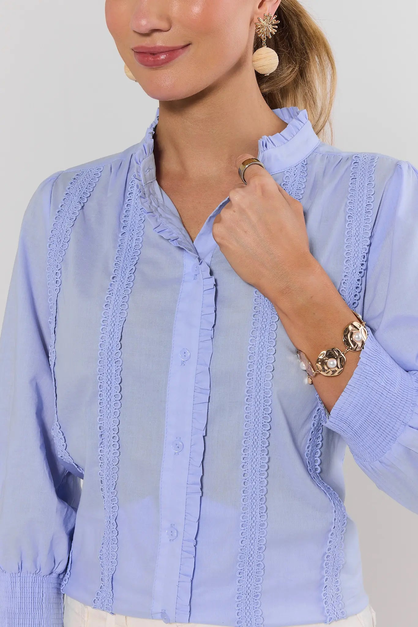 close up Woman wearing a light blue blouse with lace details on a plain background