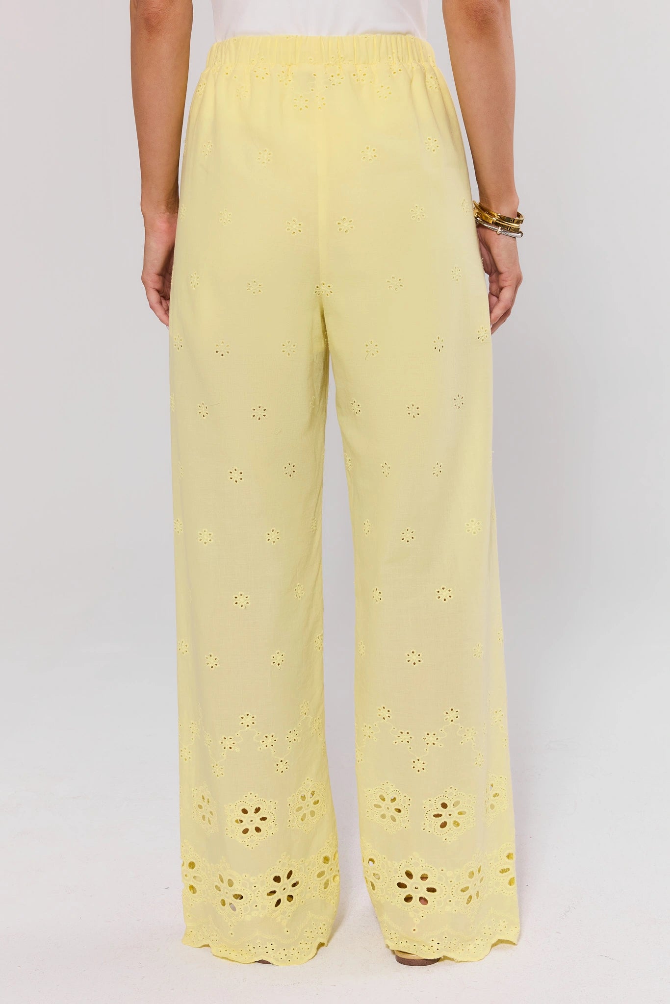 Yellow pants with floral cut-out details on a white background standing