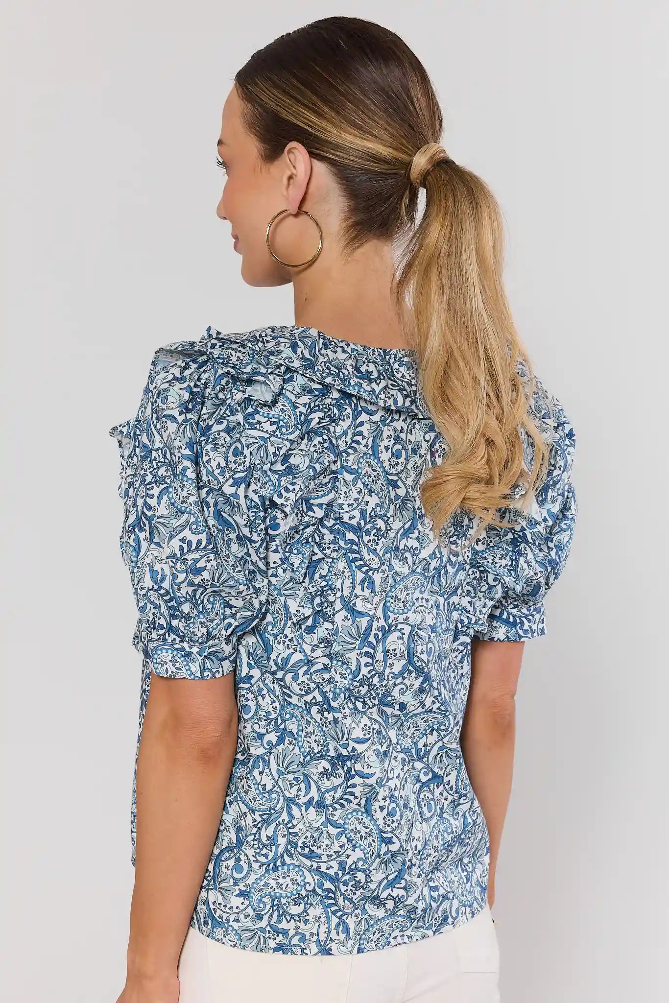 Woman wearing a blue floral blouse against a white background standing