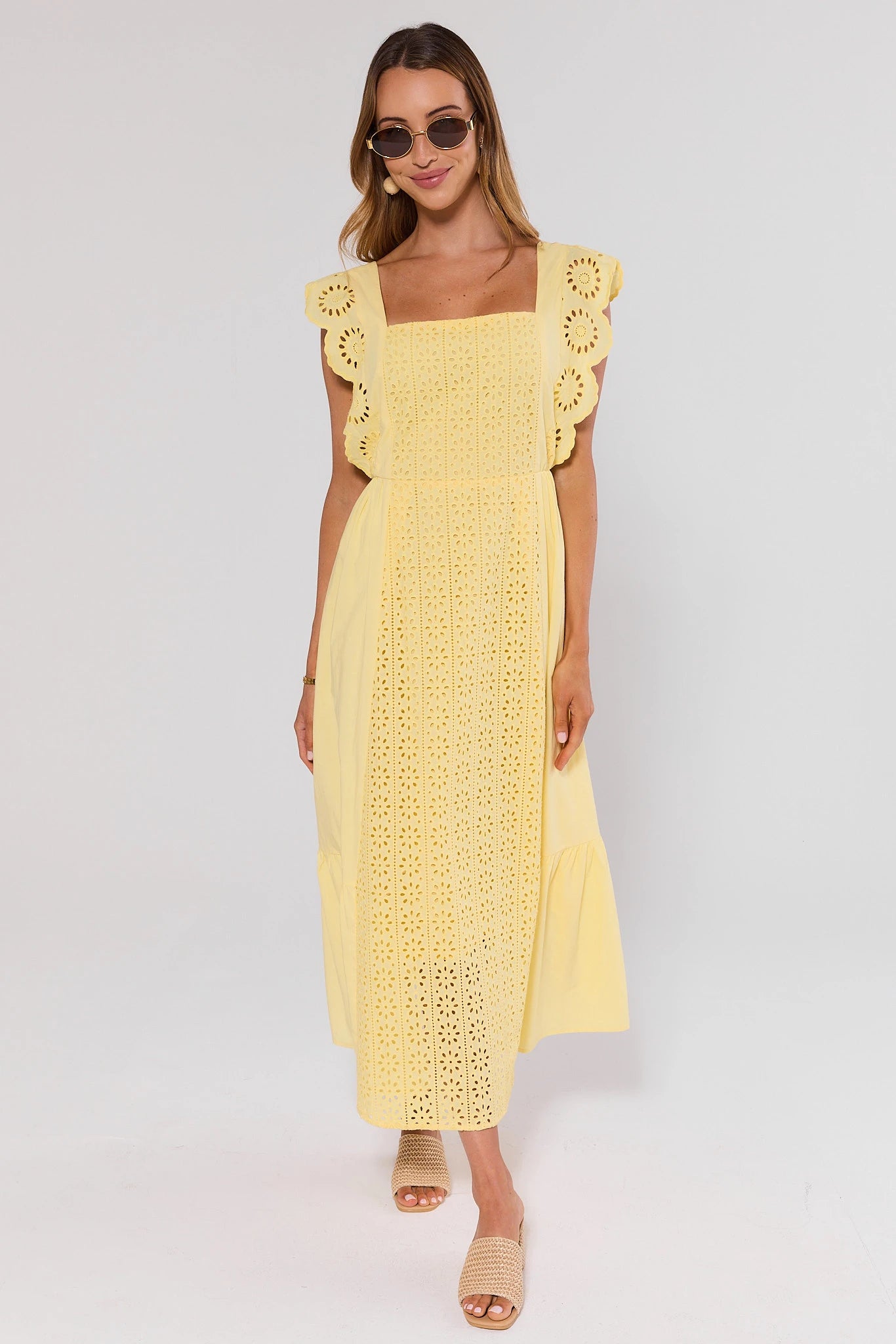 Woman wearing a yellow lace dress standing on a white background