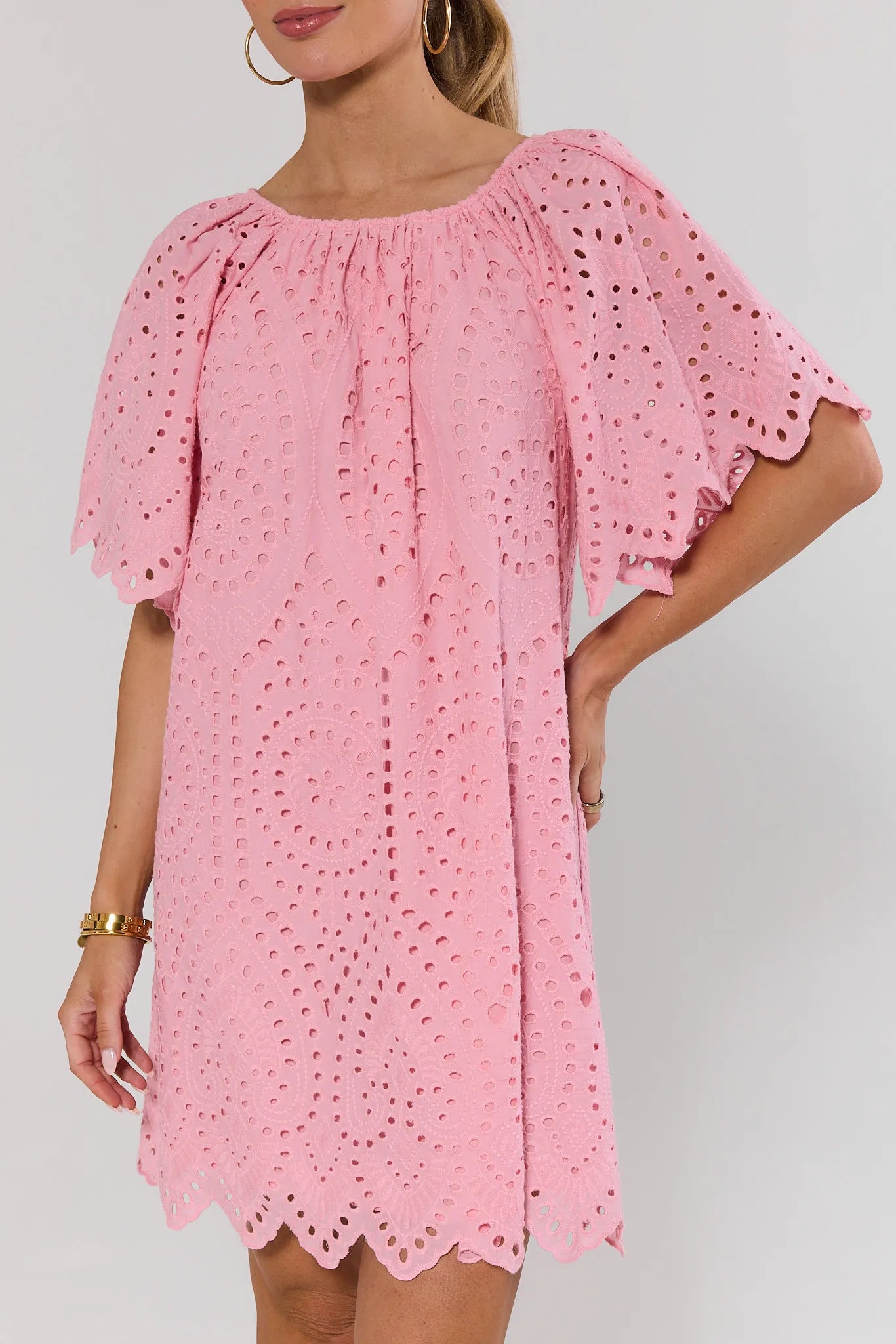 close up Pink dress with eyelet details on a plain background