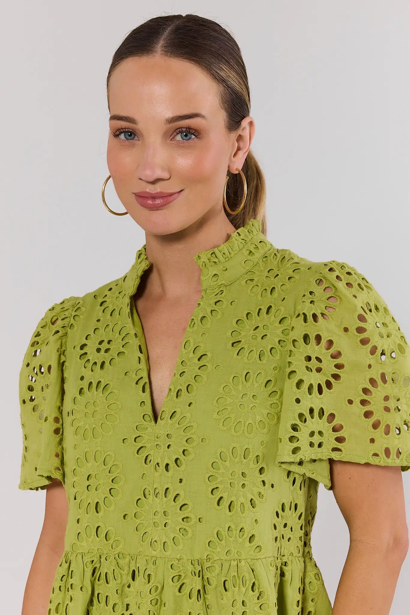 close up Woman wearing a green lace dress against a plain background